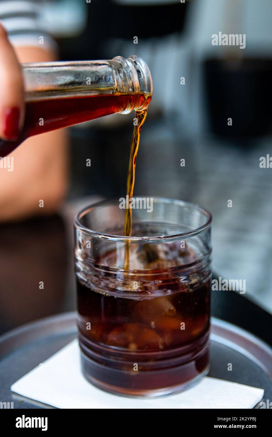 Pouring cold brew iced coffee in glass cup with ice cubes , coffee