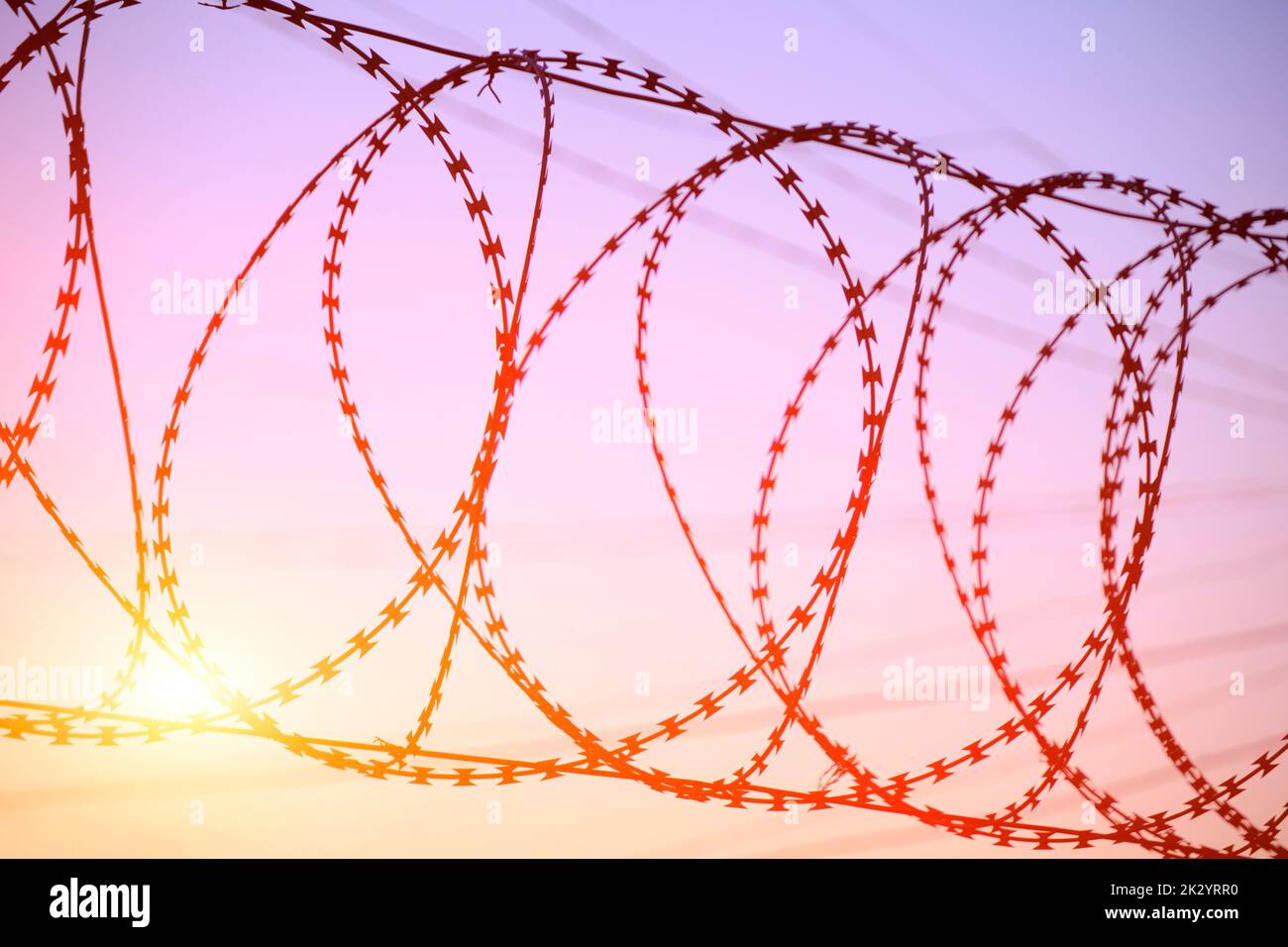 Fence with barbed wire background bright red setting sun Stock Photo ...