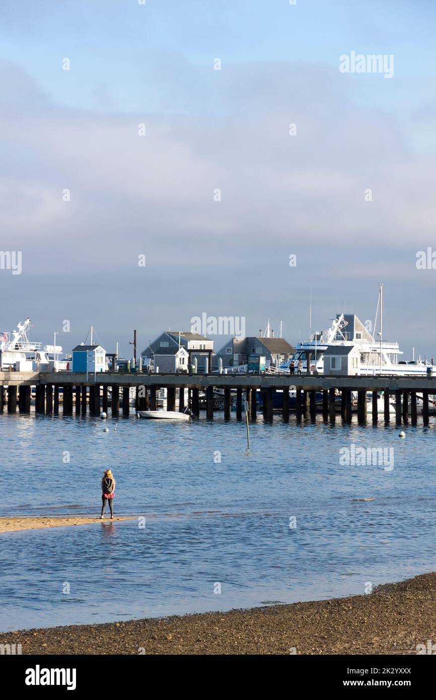 Visitor/tourist viewing MacMillan Wharf/Pier from a sand bar in Provincetown, Cape Cod, Massachusetts. Stock Photo