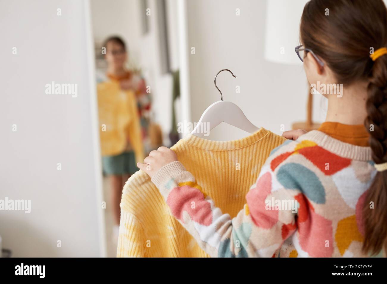 Back view at teenage girl choosing clothes and looking at mirror at home, copy space Stock Photo