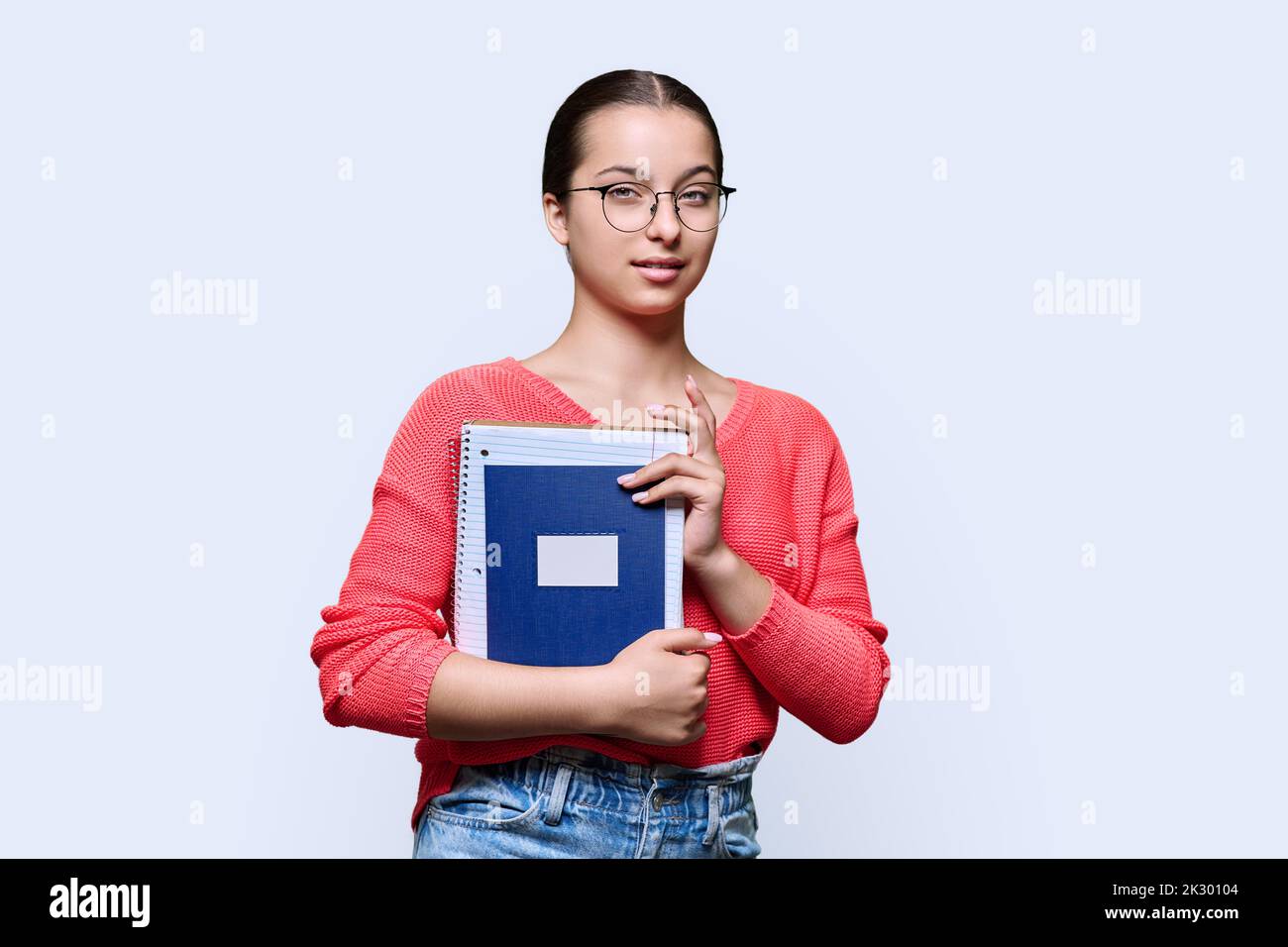 Portrait of teenage female student holding notebooks looking at camera ...