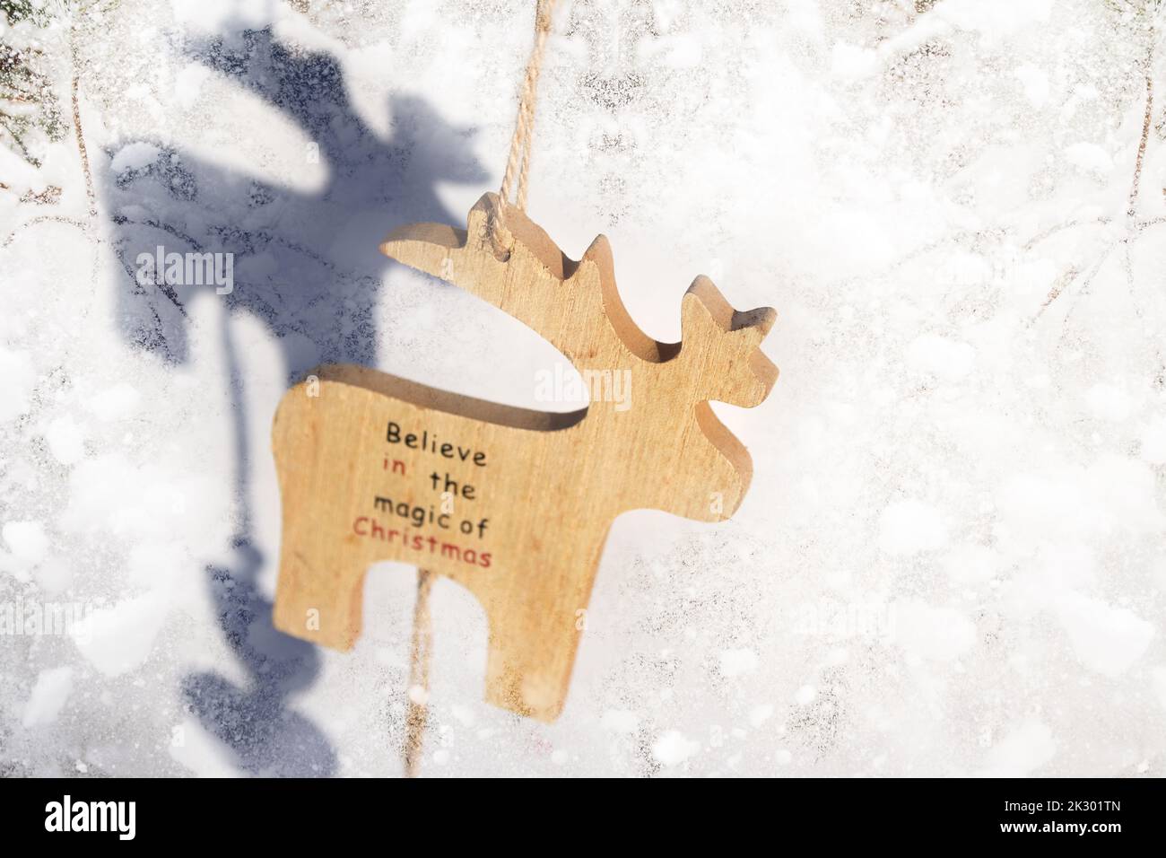 Defocus Christmas reindeer toy on brick background, sunny. Wooden small model winter deer toy on snowy background. Christmas deer hanging. Winter holi Stock Photo