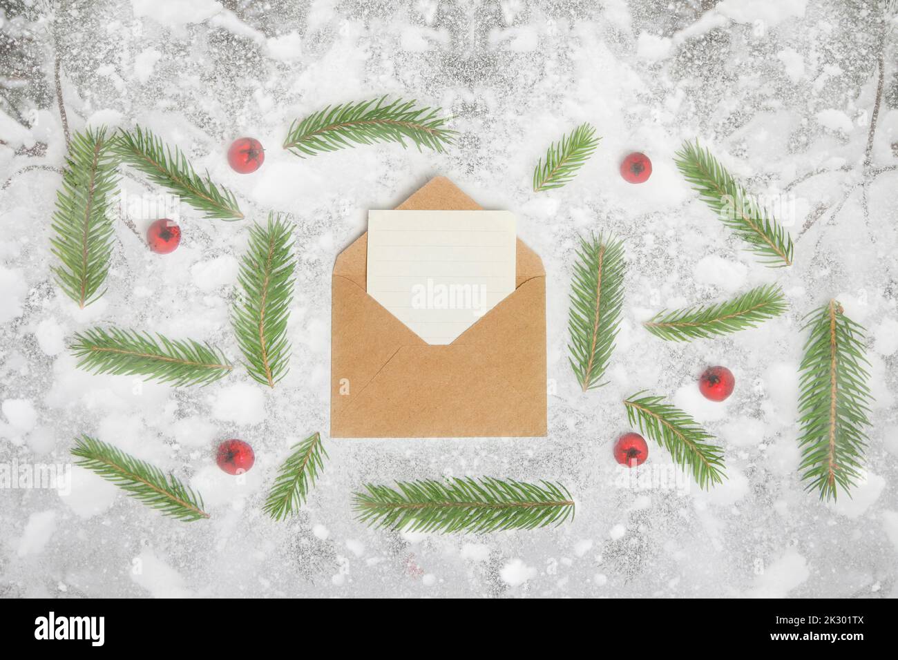 Defocus eco craft envelope, letter to Santa. Frame of fir branch or spruce branch and red berries on snowy background. Fir tree branches. Christmas gr Stock Photo