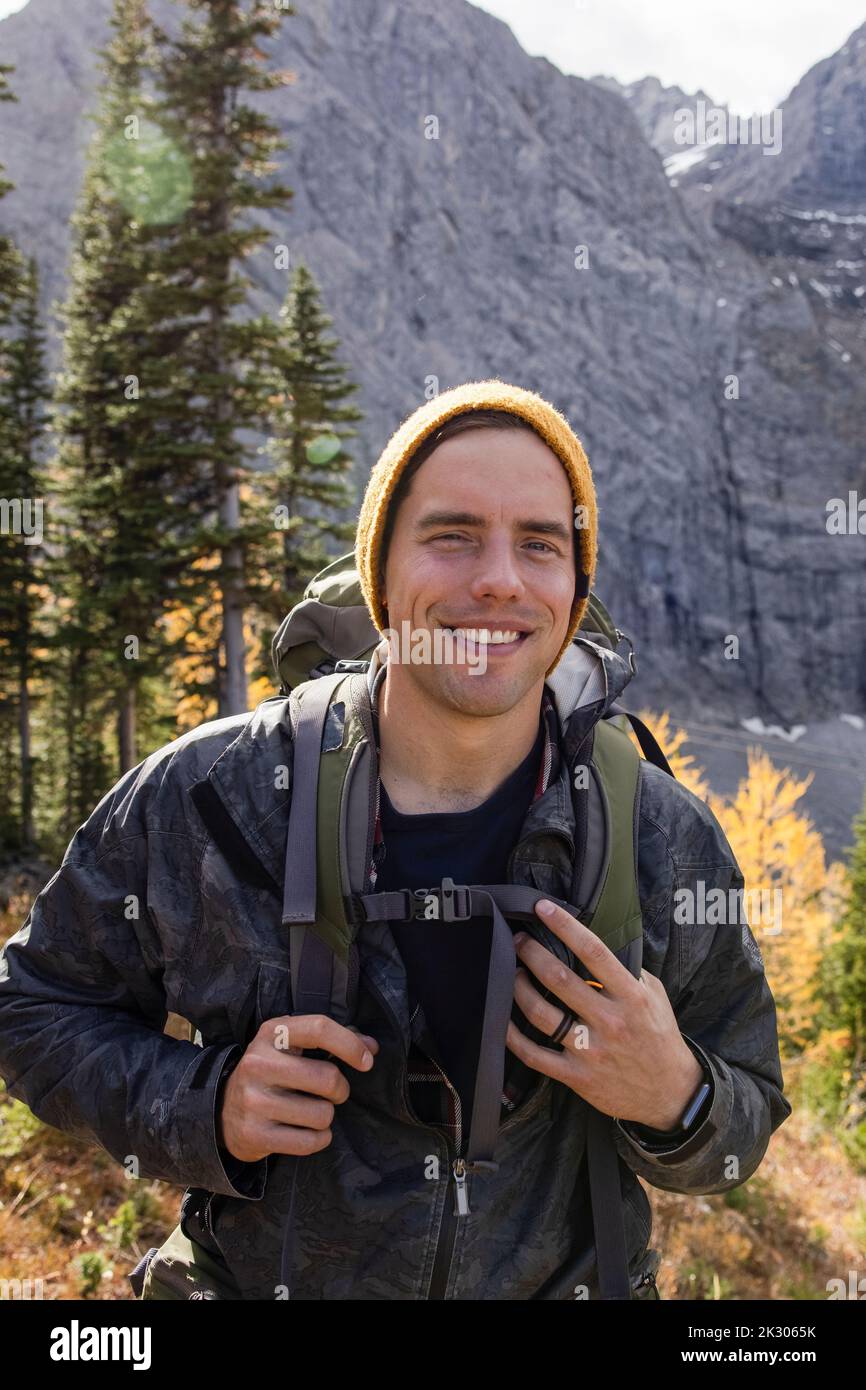 Portrait happy male backpacker in sunny autumn woods Stock Photo