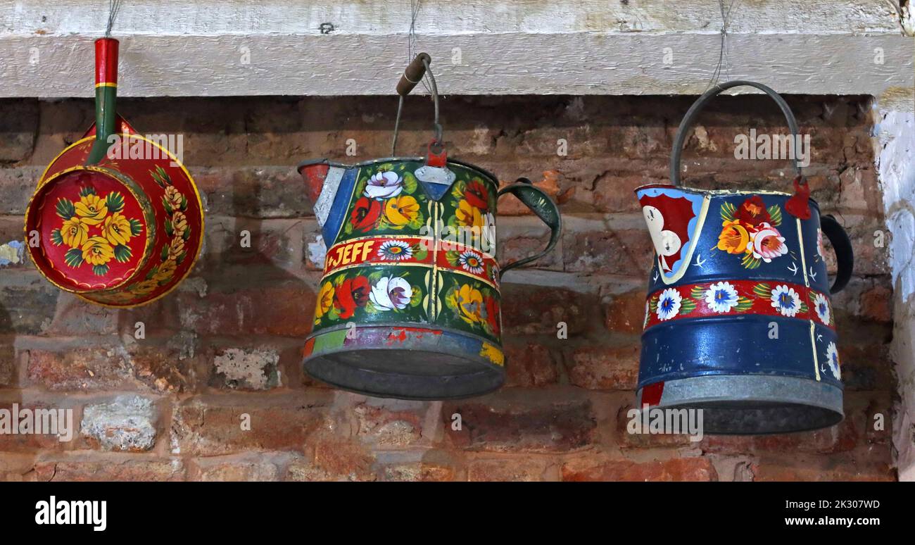 Traditional hand-painted canal barge ware, pan, watering pail, bucket, pans, hanging up, on an English waterway - flower designs Stock Photo