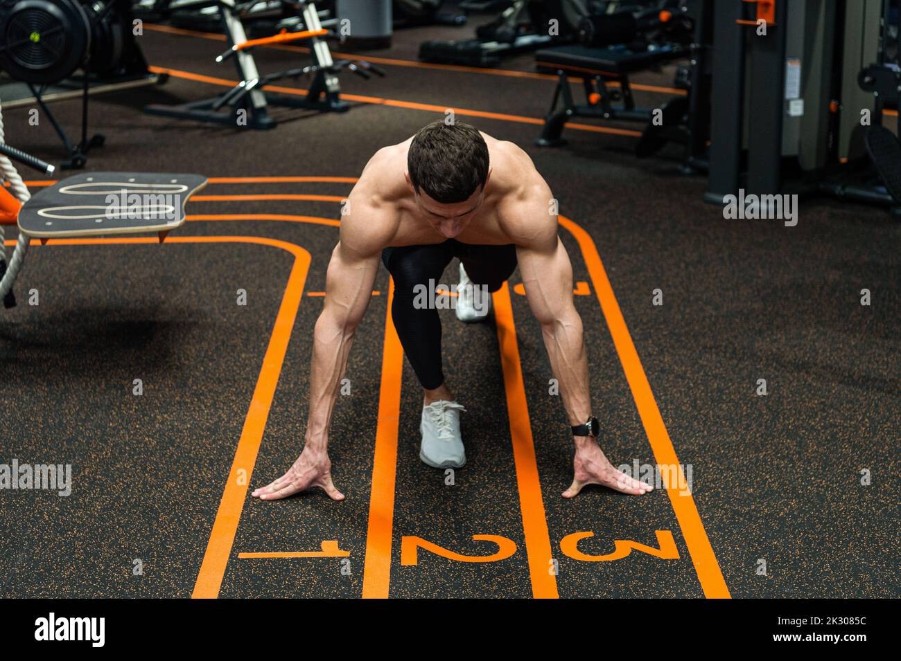 Athlete in crouch position with front knee over and hands on starting ...