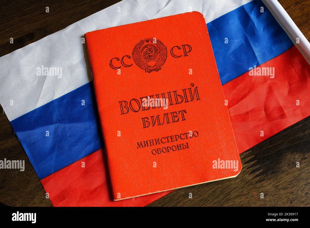 Certificate of Soviet Union serviceman and Russian flag on table. Concept of mobilization in Russia, war in Ukraine, soldier, duty and army. Translati Stock Photo