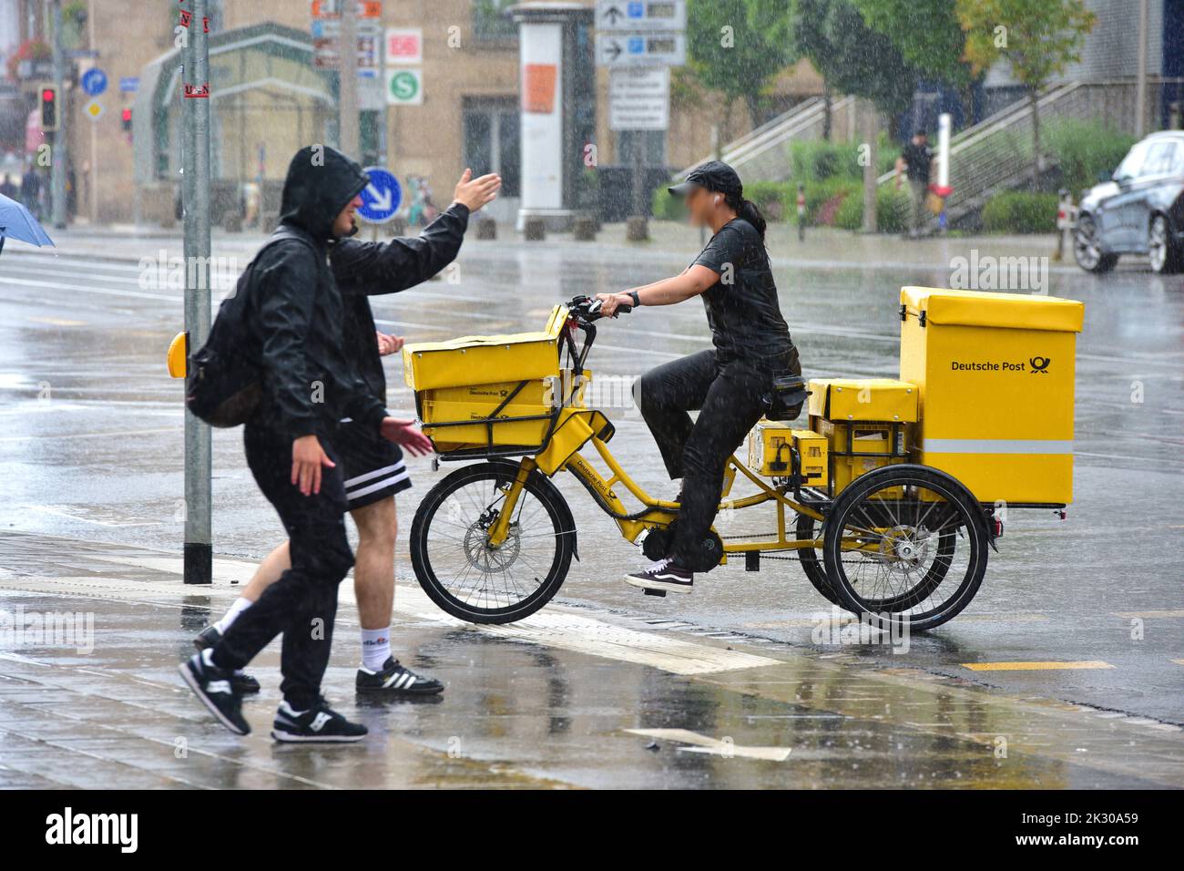 Deutsche Post delivery woman on a bicycle in the rain in the center of Nuremberg Stock Photo