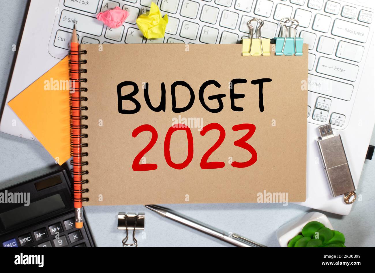 On a pink background, reports, black paper clips, glasses and a white notebook with the text BUDGET 2023. Stock Photo