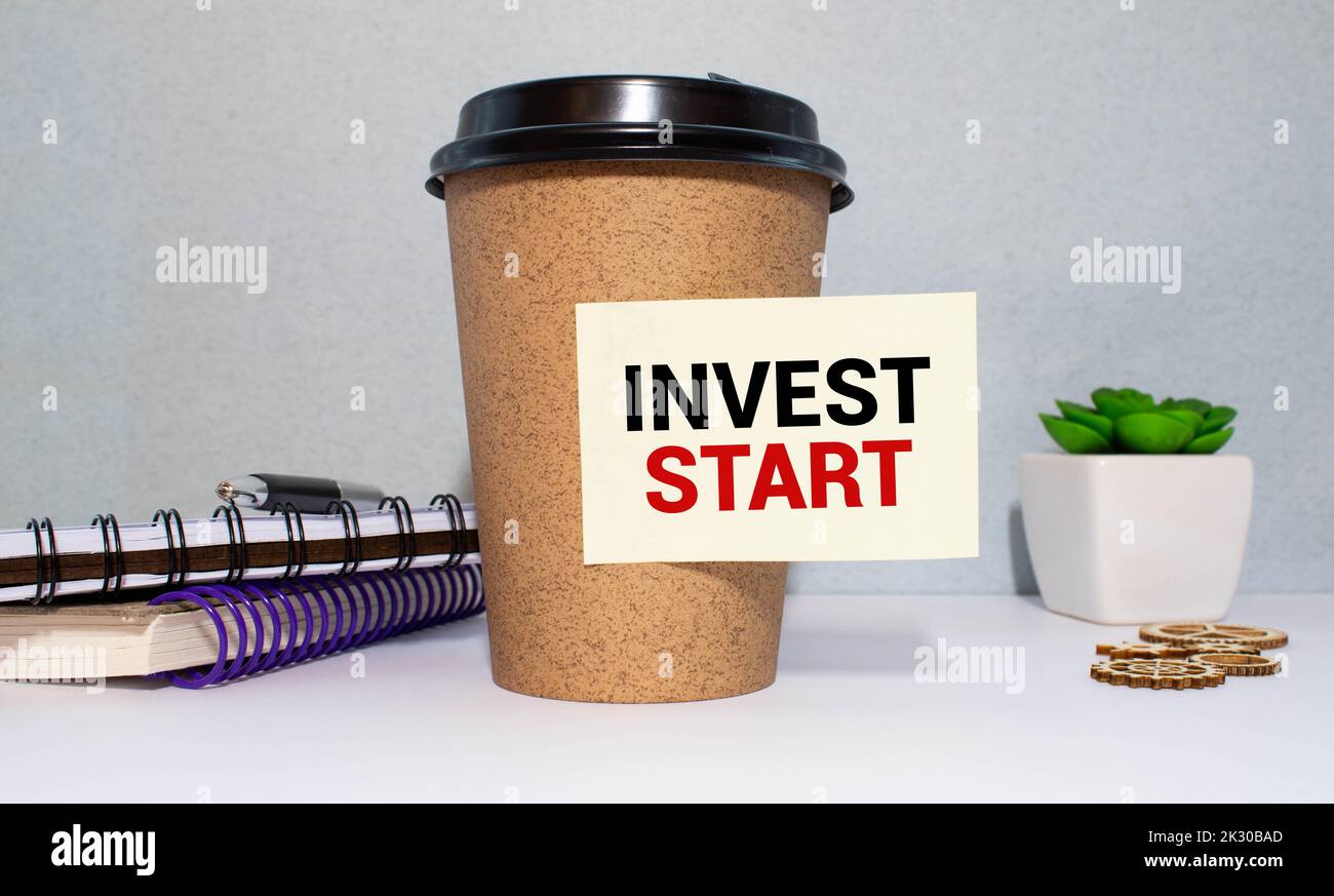Finance and business concept. On a gray background, a red zipper unfastens, on a white surface the inscription - INVEST START Stock Photo