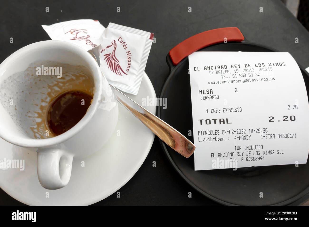 Coffee espresso cup just emptied with a receipt for it totaling EURO 2.20. El Anciano Rey cafeteria, Madrid, Spain Stock Photo