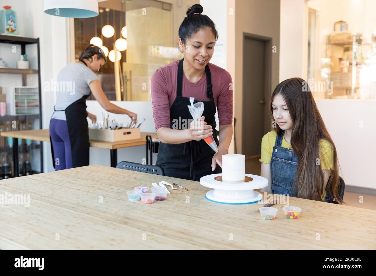 Woman teaching teen girl to decorate cake Stock Photo