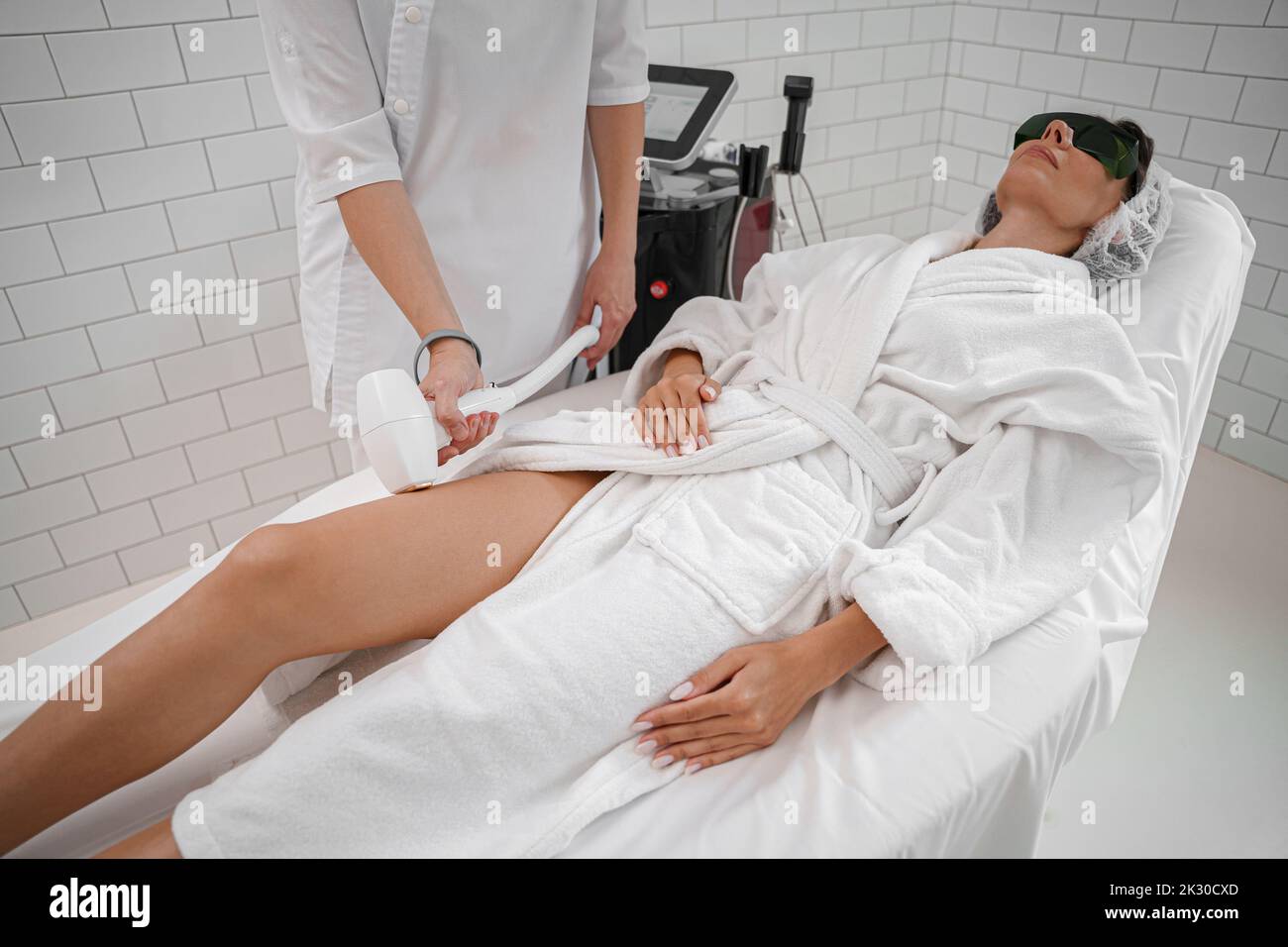 Woman getting hair removing procedure on legs. Laser epilation and cosmetology in beauty salon Stock Photo