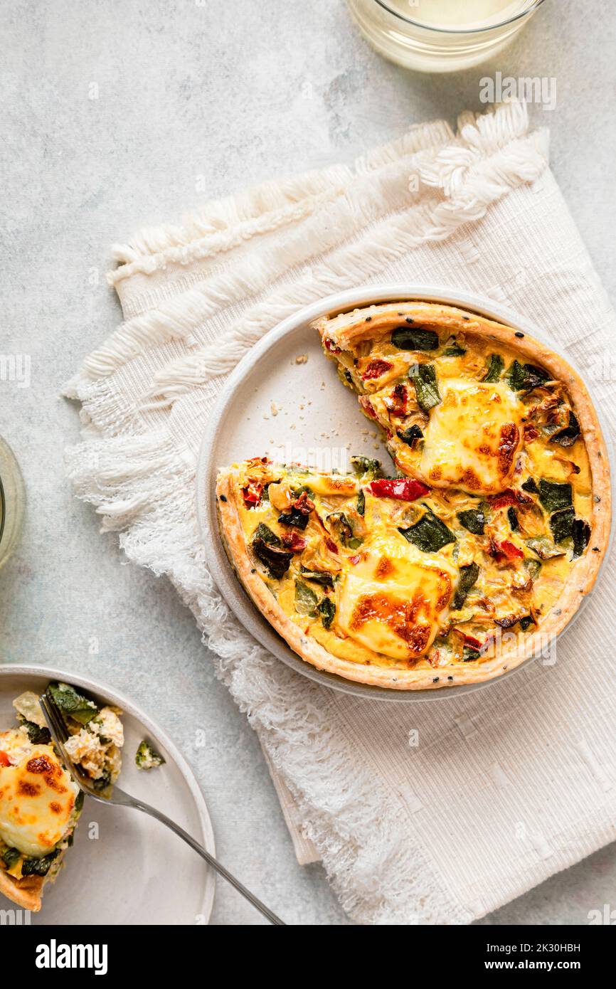 Studio shot of freshly baked zucchini quiche with red bell pepper and onion Stock Photo