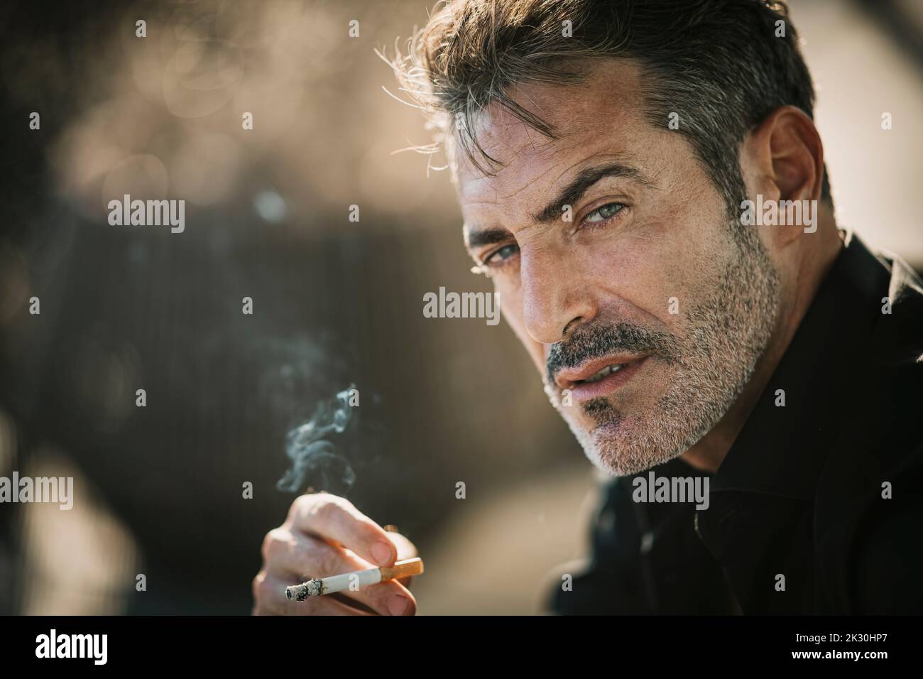 Handsome man with hair stubble smoking cigarette Stock Photo