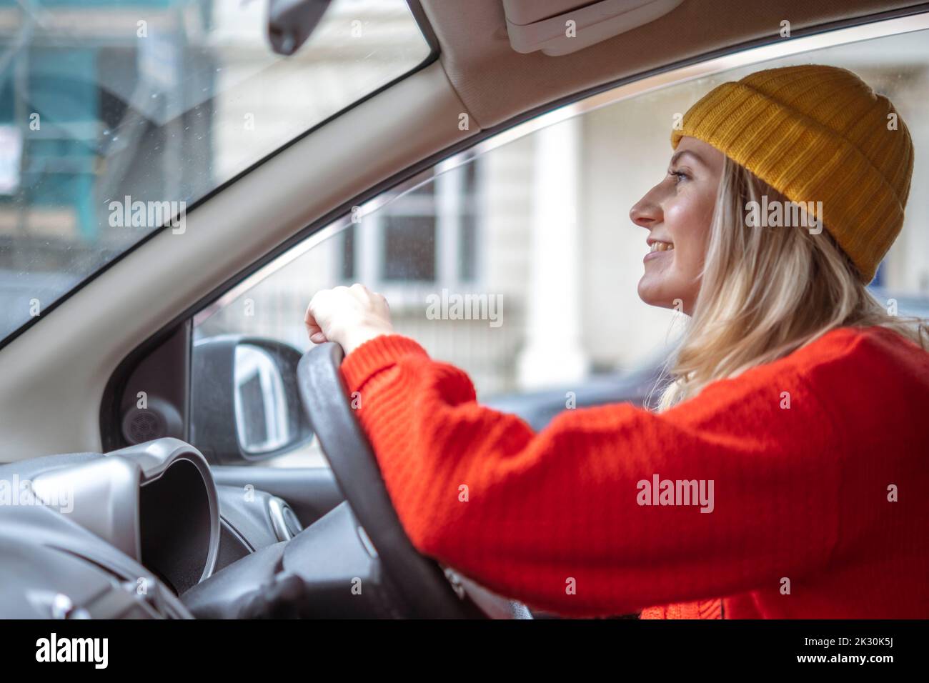 Smiling woman in knit hat driving car Stock Photo