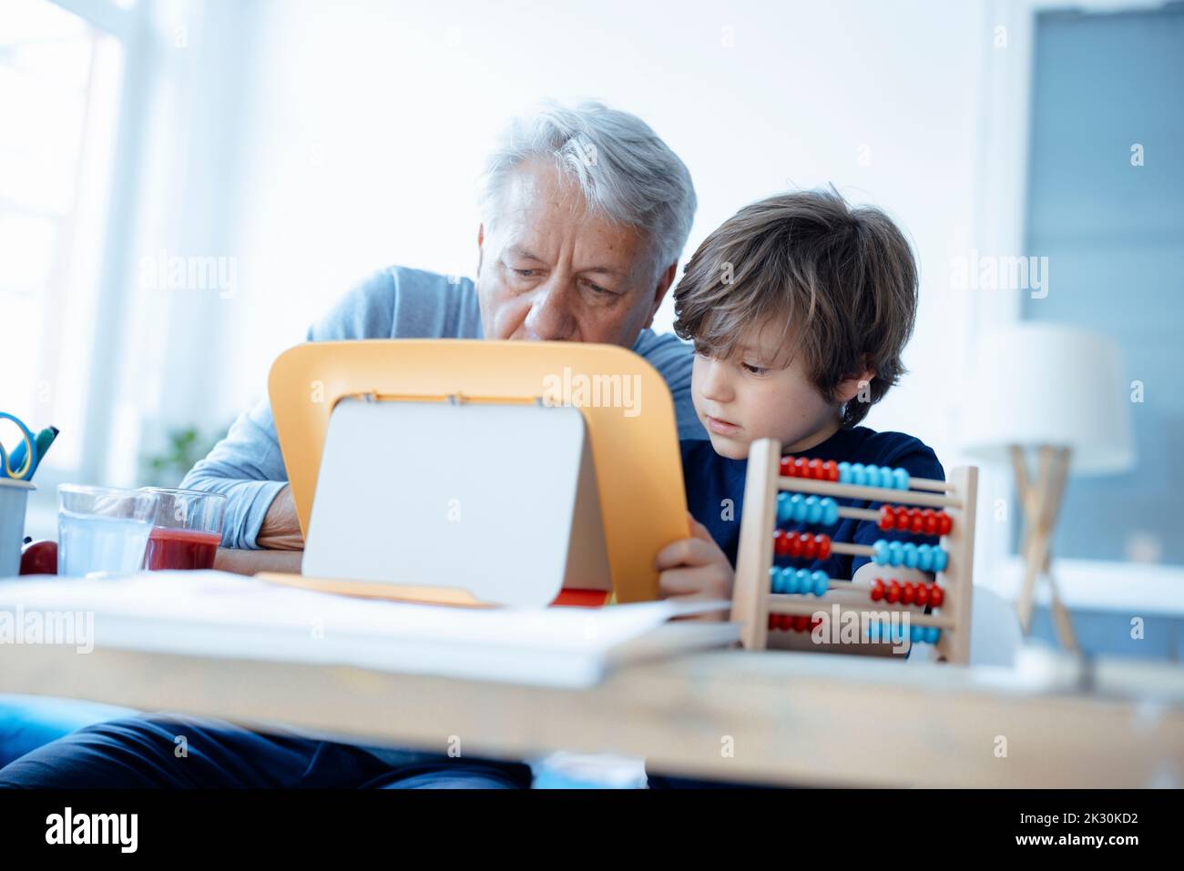 Senior man and boy using tablet PC at home Stock Photo