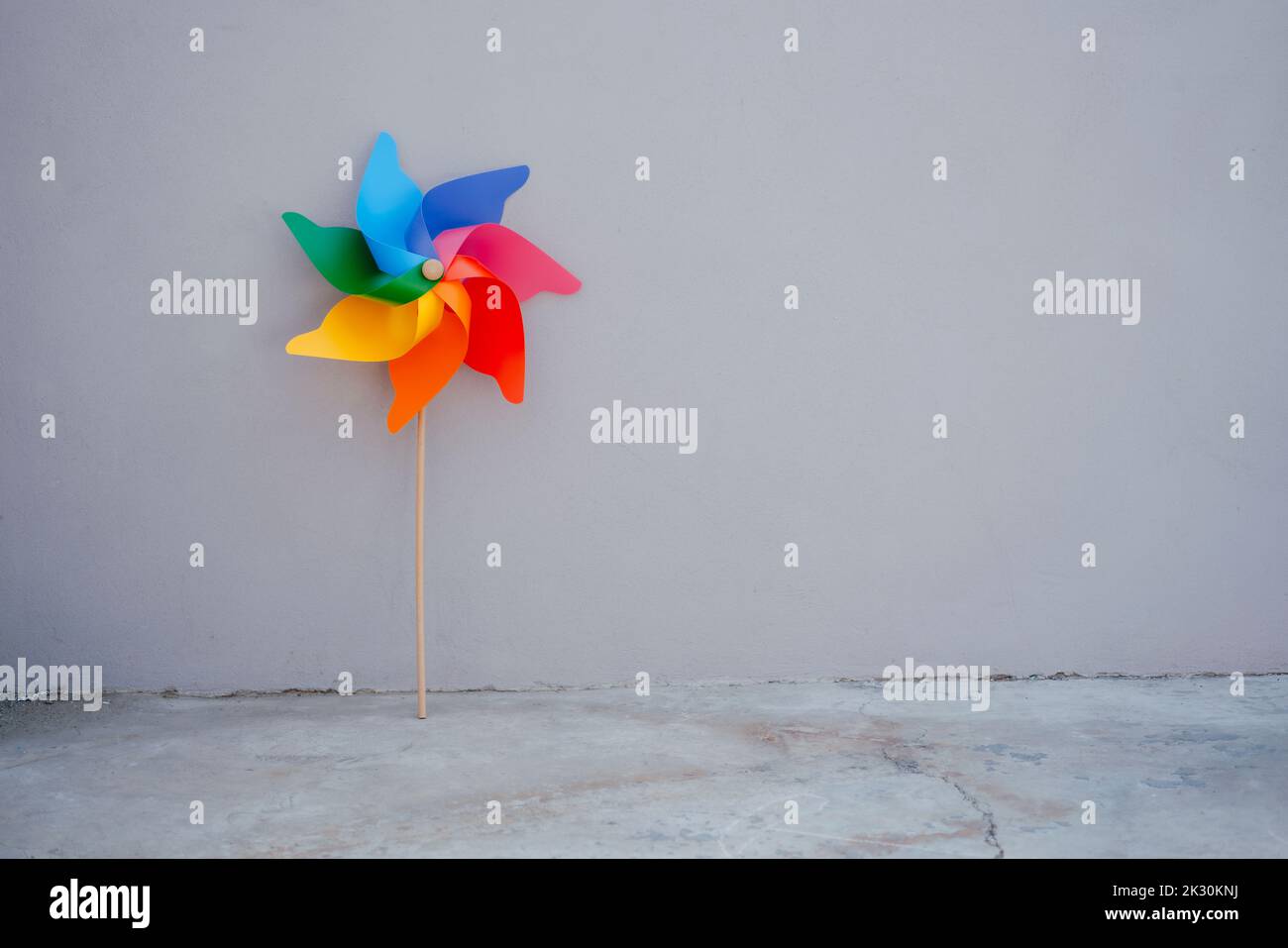 Multi colored pinwheel toy in front of gray wall Stock Photo - Alamy