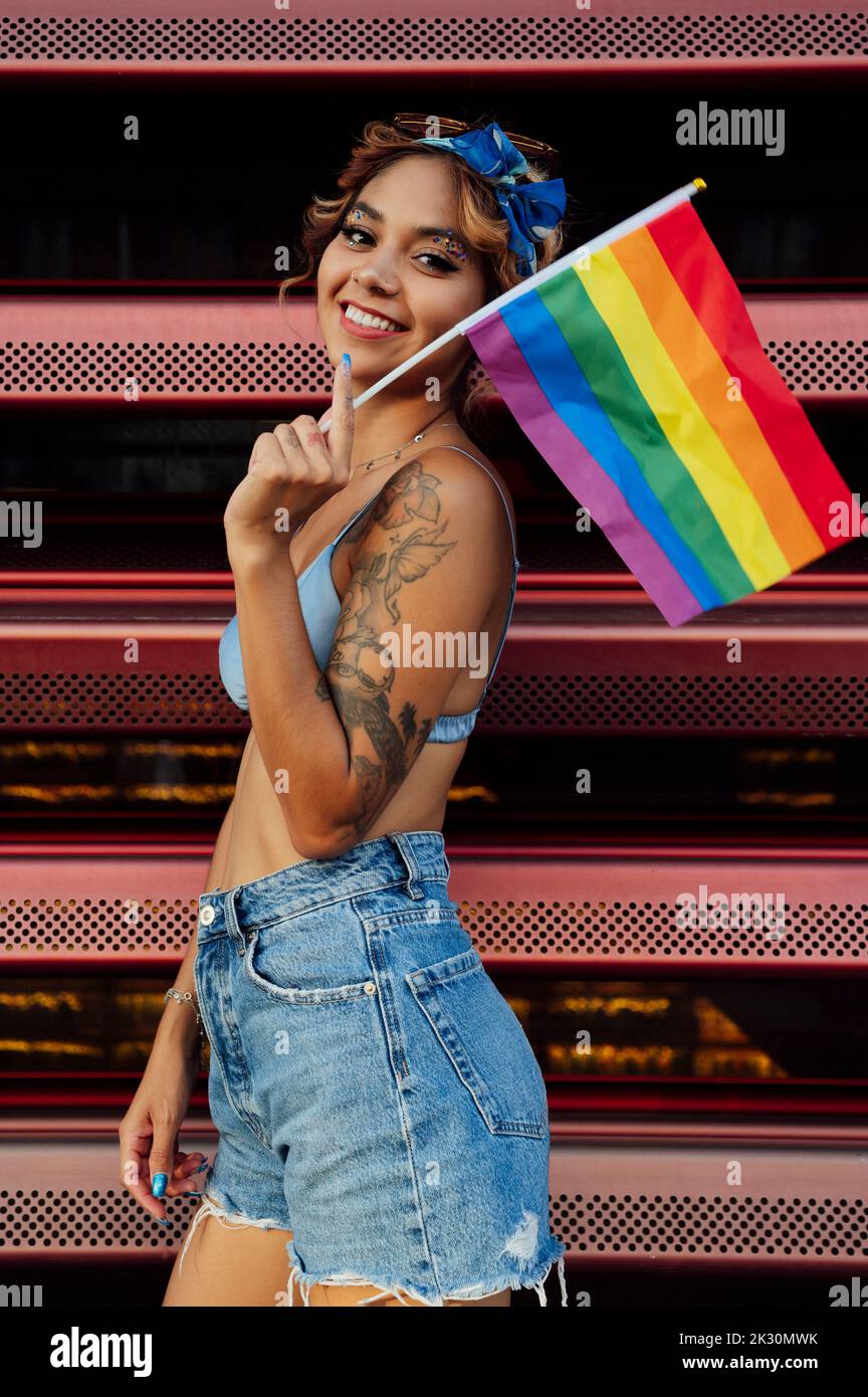 Smiling young woman with rainbow flag in front of shutter Stock Photo ...