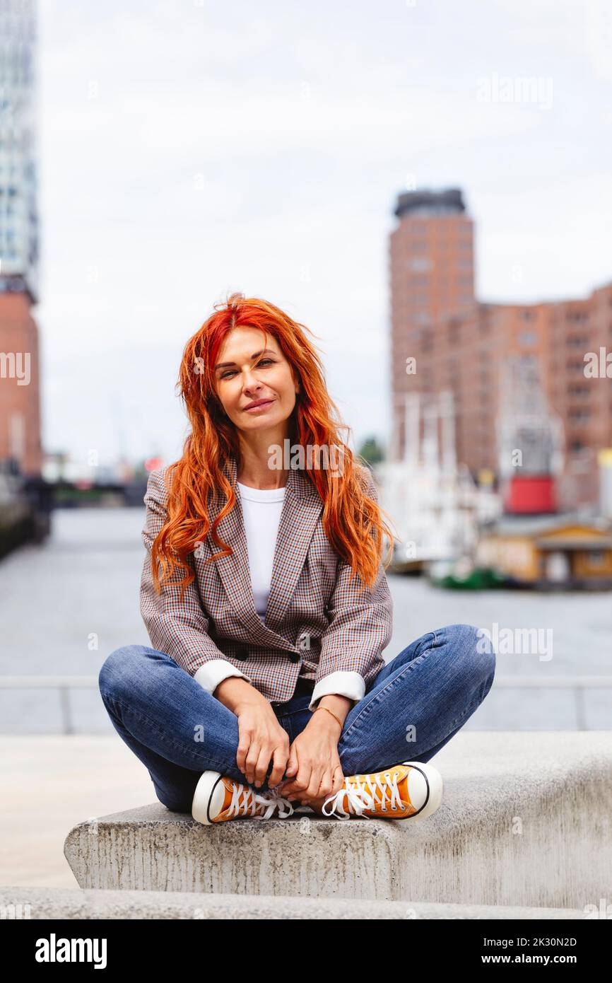 Happy redhead woman sitting on bench at Hafencity Stock Photo - Alamy