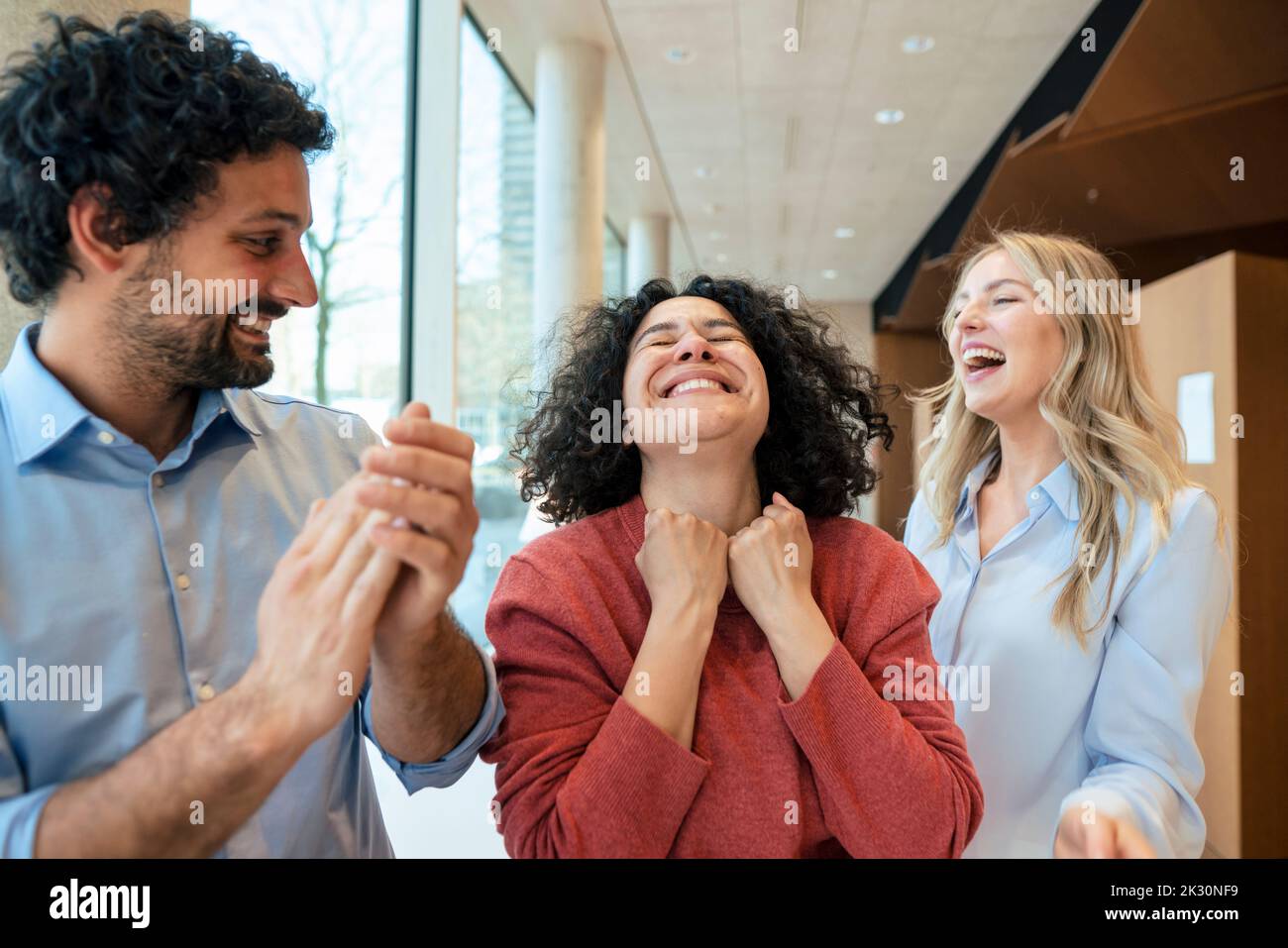 Happy woman celebrating success with colleagues in library Stock Photo