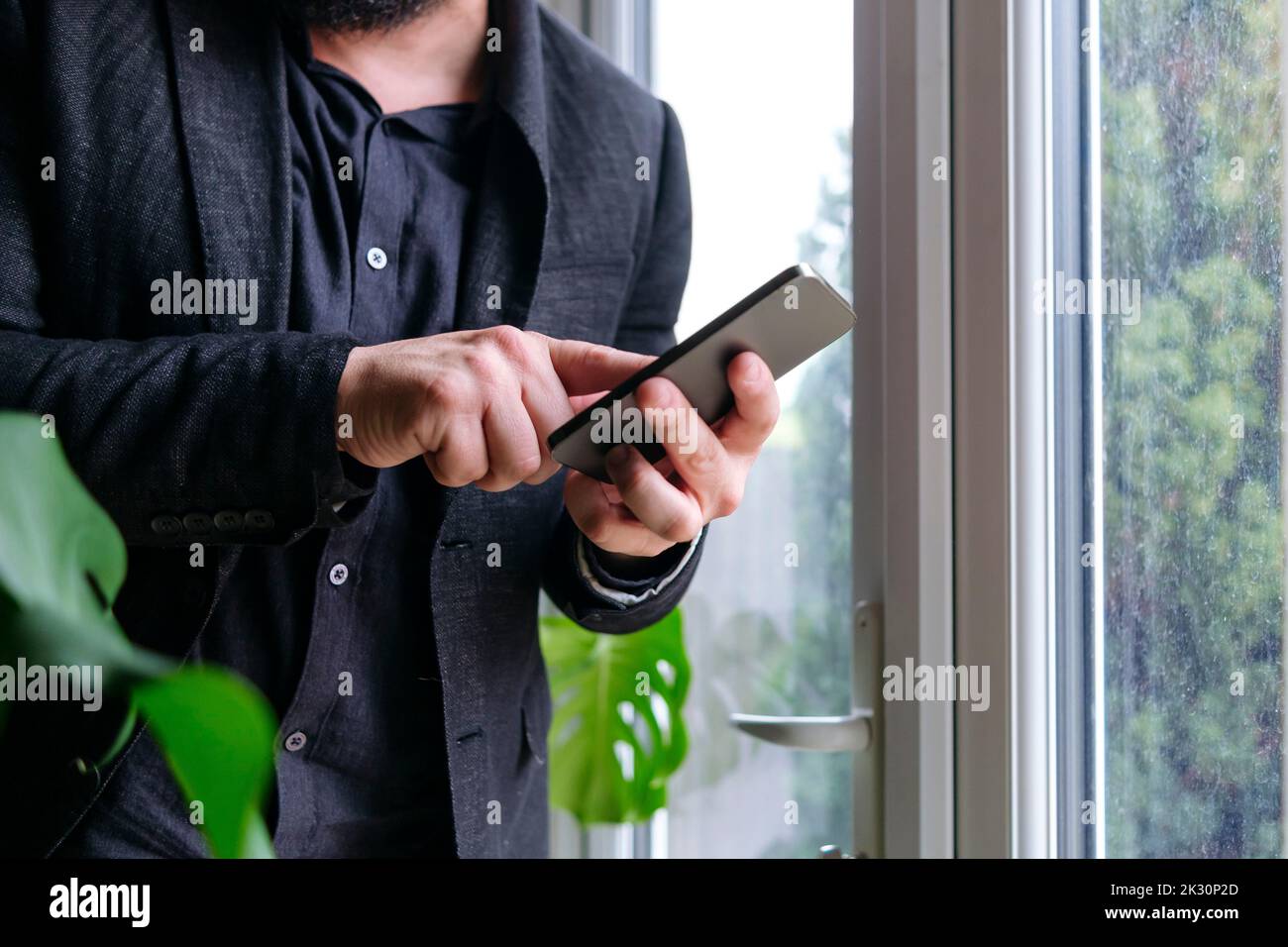 Businessman using smart phone by window at home Stock Photo
