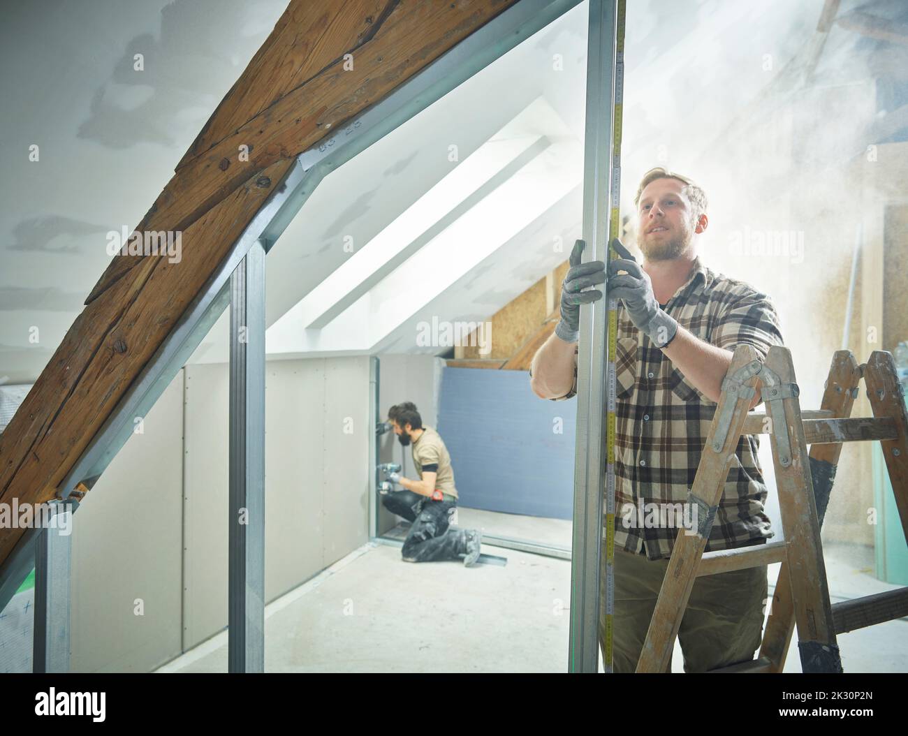 Construction worker measuring metal for drywall at site Stock Photo