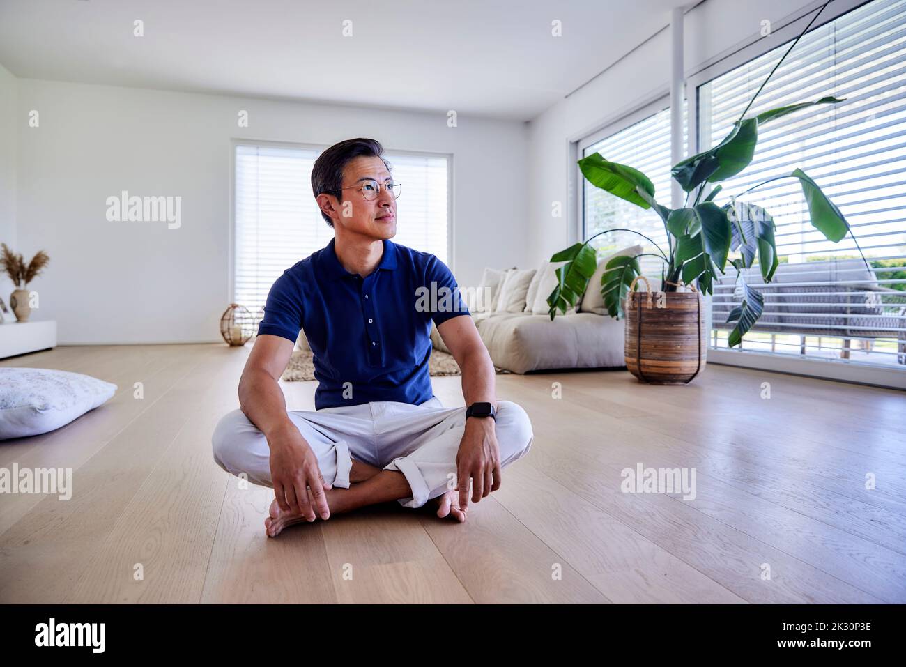Smiling mature man sitting cross-legged on floor at home Stock Photo ...