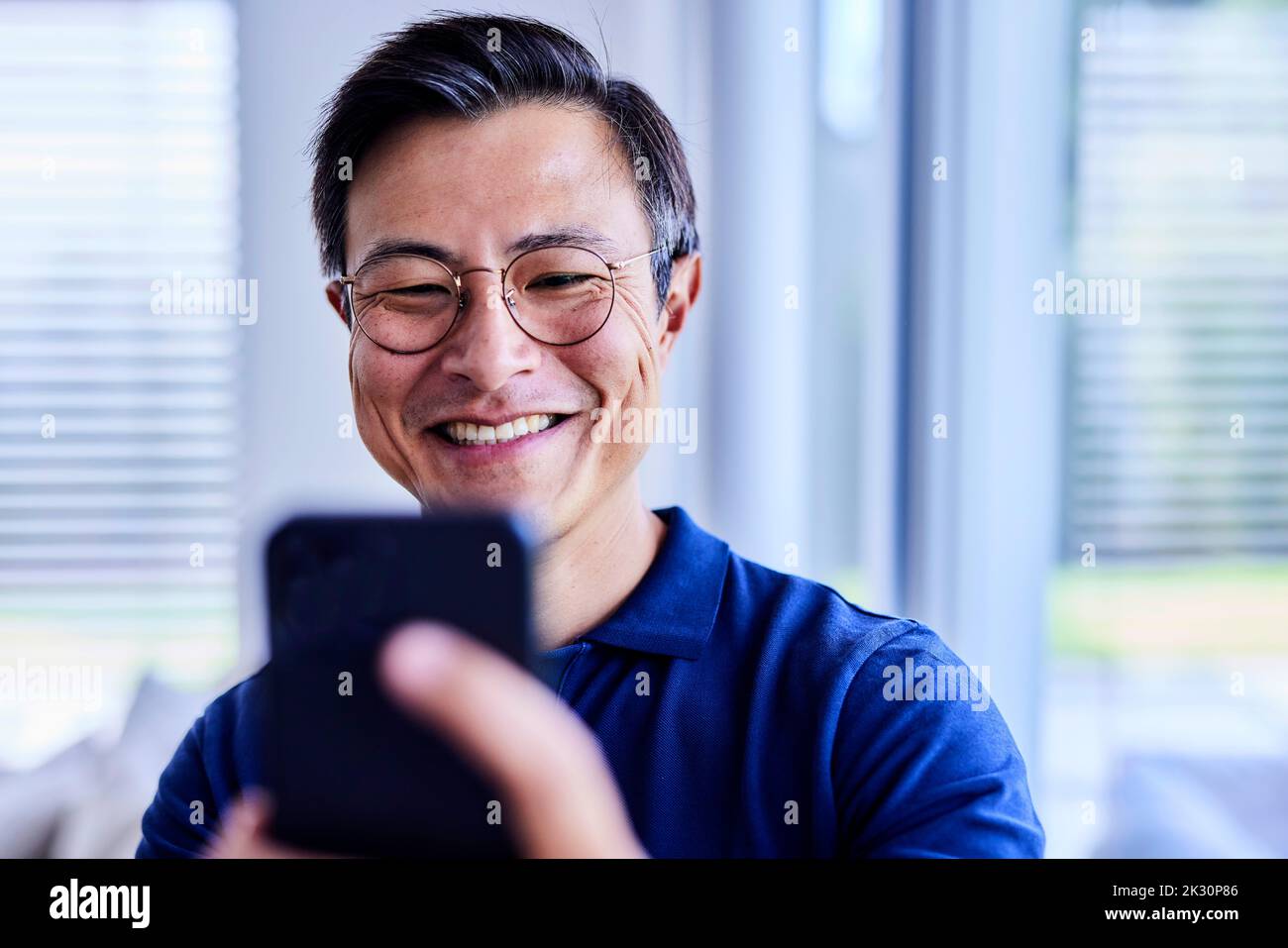 Happy man wearing eyeglasses taking selfie through mobile phone Stock