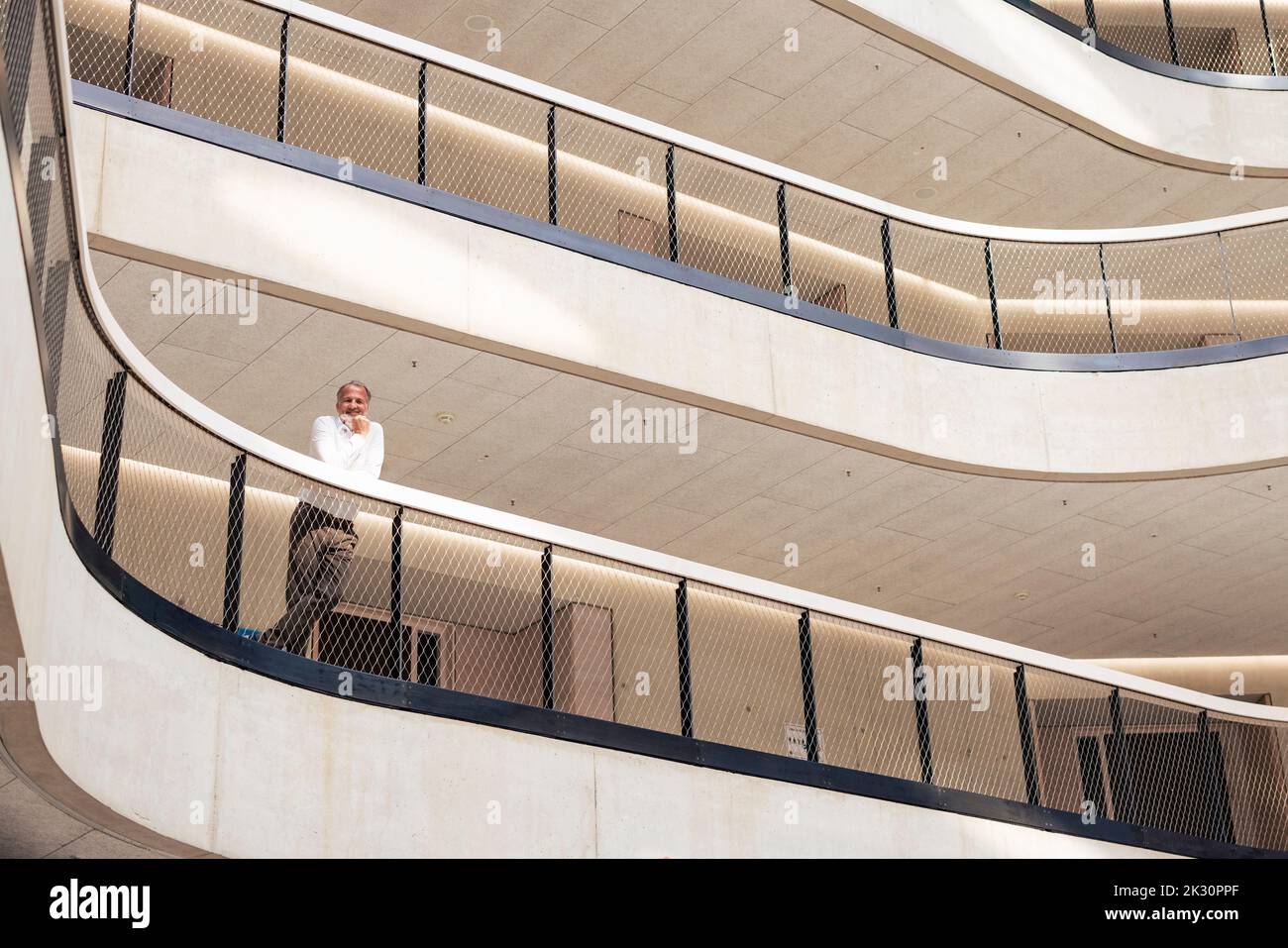 Senior businessman leaning on railing in corridor Stock Photo - Alamy