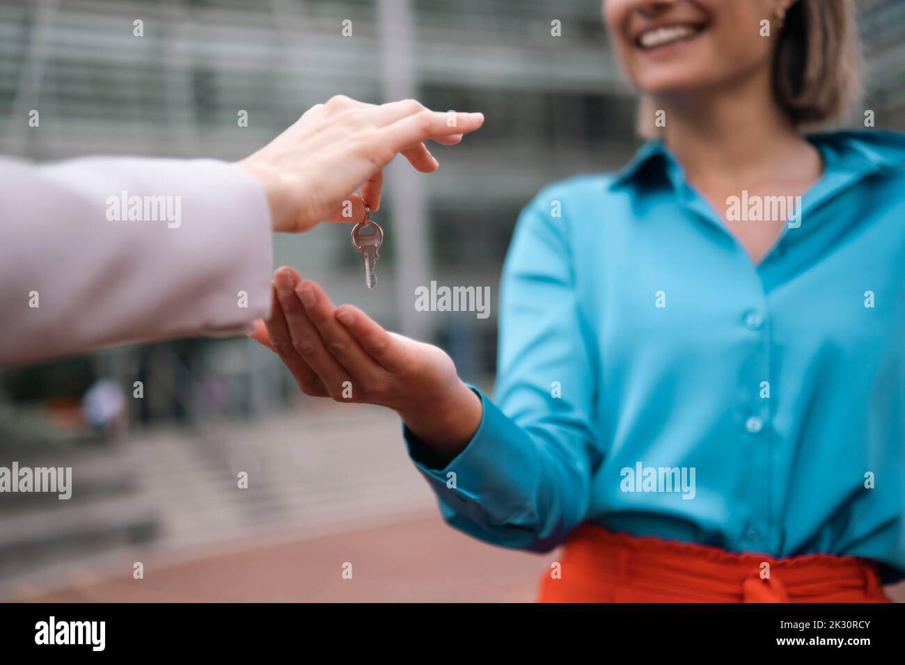 Hand of real estate agent giving house key to smiling customer Stock ...