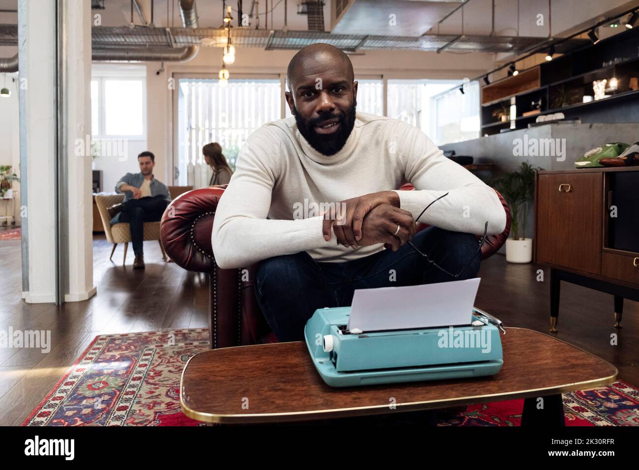 Confident businessman sitting in armchair using typewriter Stock Photo