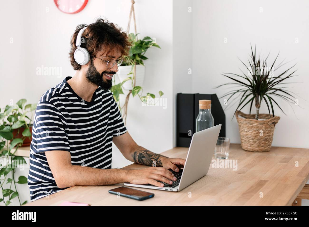 Freelancer wearing wireless headphones working on laptop in home office