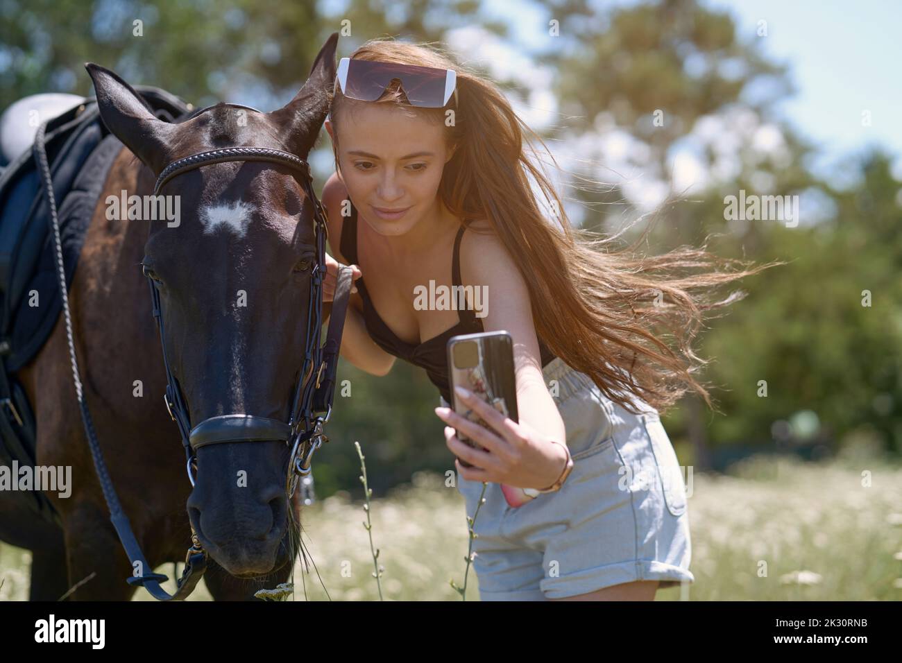 Beautiful woman with horse taking selfie through smart phone on sunny
