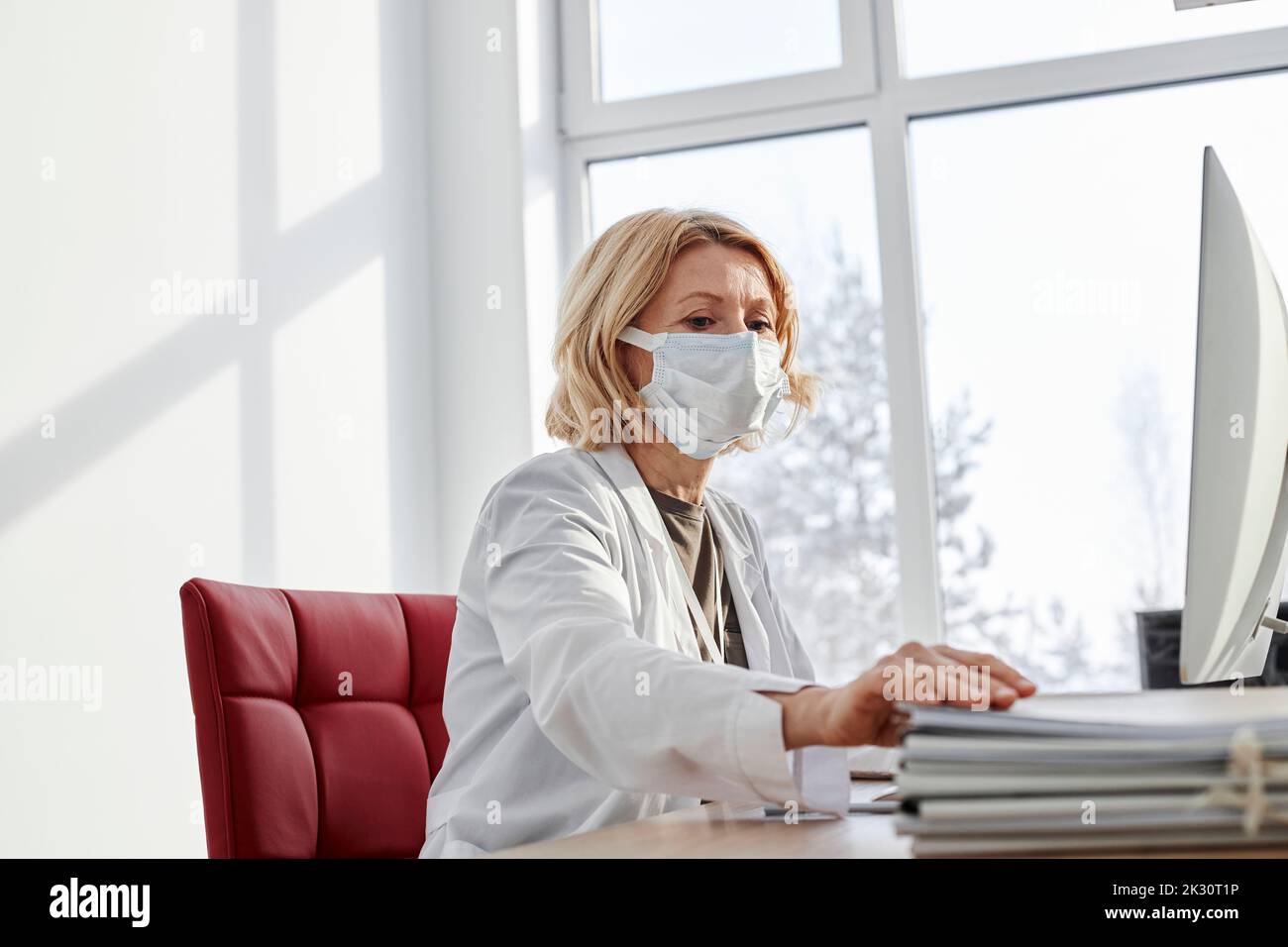 Doctor doing paperwork wearing protective face mask in clinic Stock Photo
