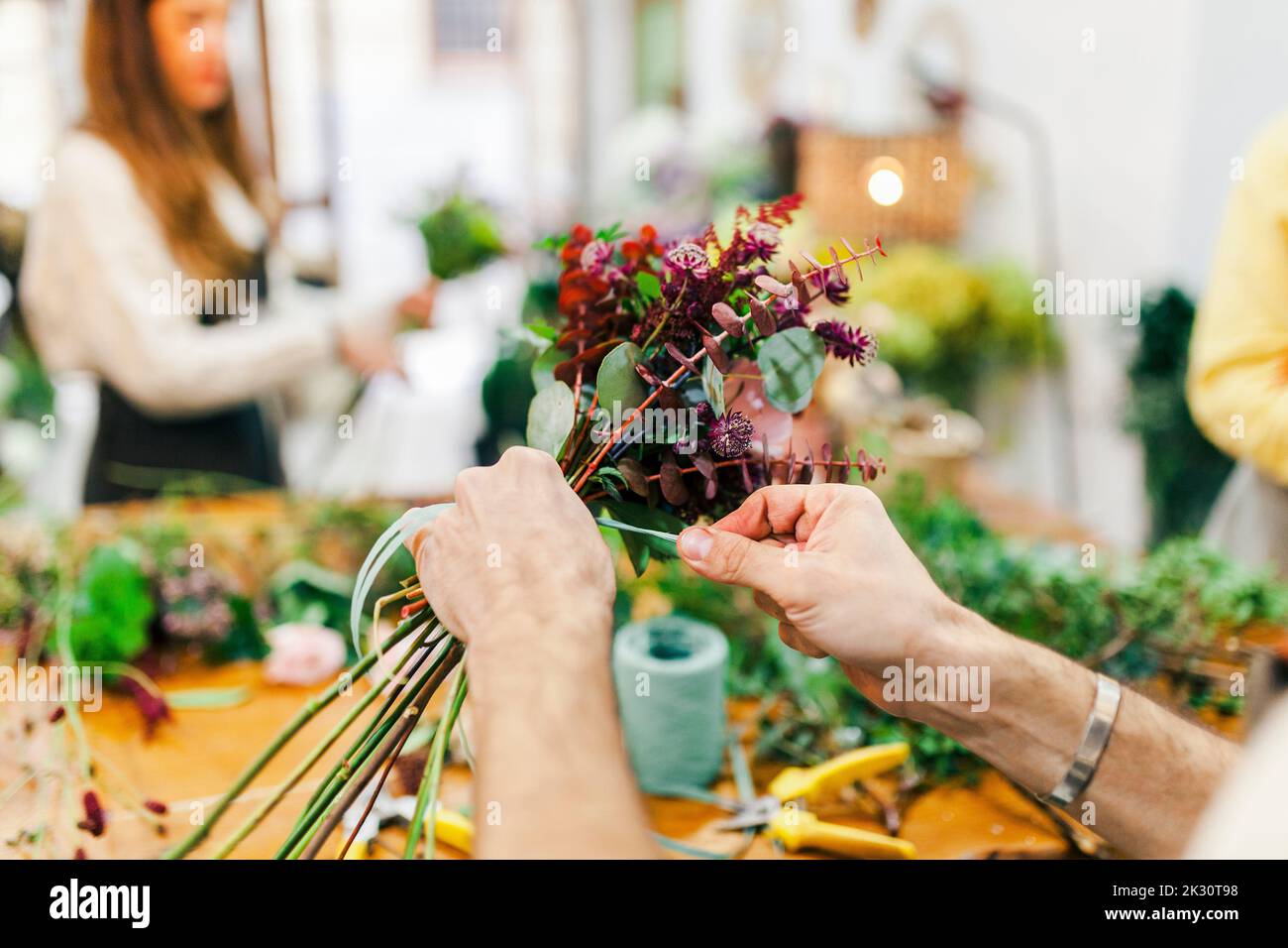 Hands of florist tying plants at flower shop Stock Photo
