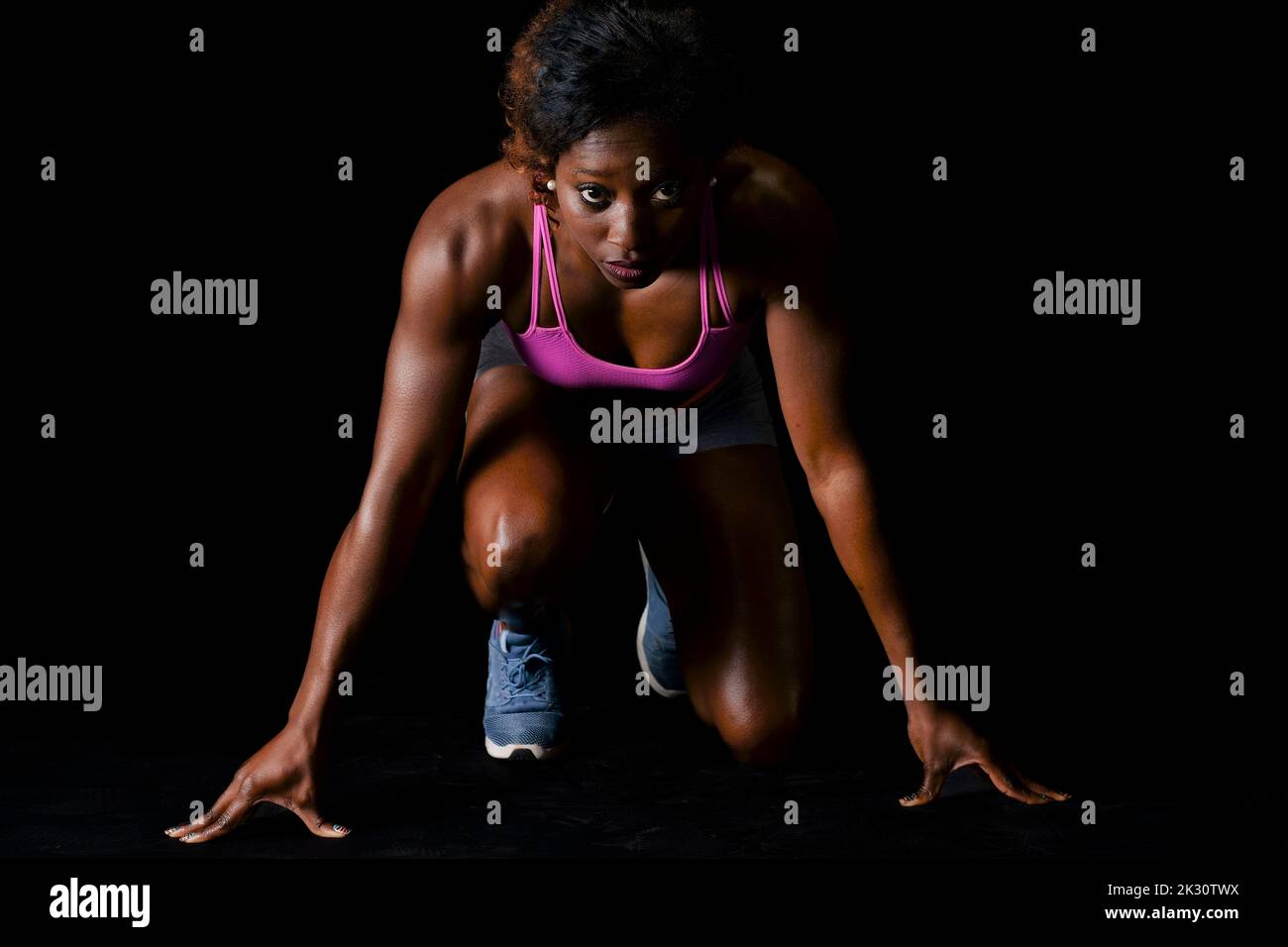 Athlete in starting position for running against black background Stock Photo