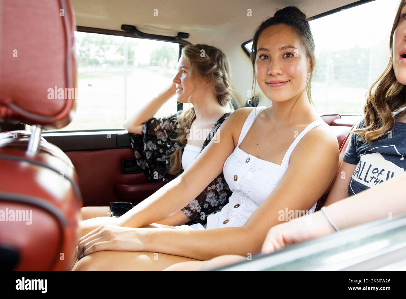 Portrait happy teenage girl riding in back seat of car with friends Stock Photo