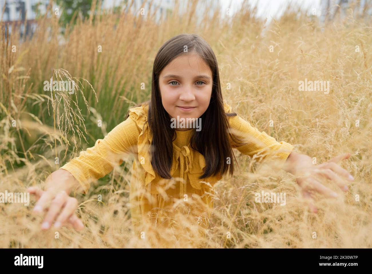 Smiling pre-adolescent girl amidst grass in field Stock Photo