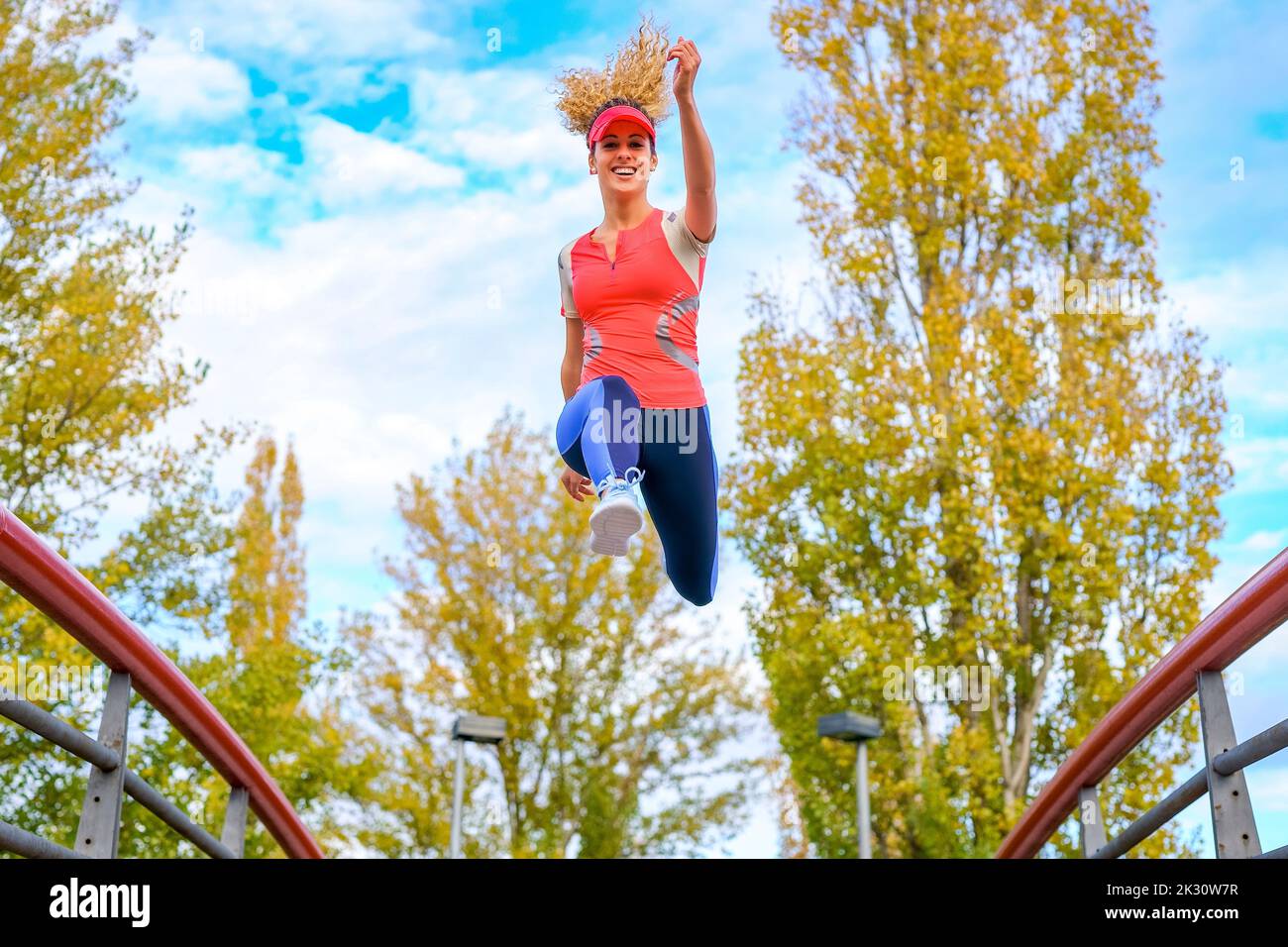 Smiling young athlete jumping on footbridge Stock Photo