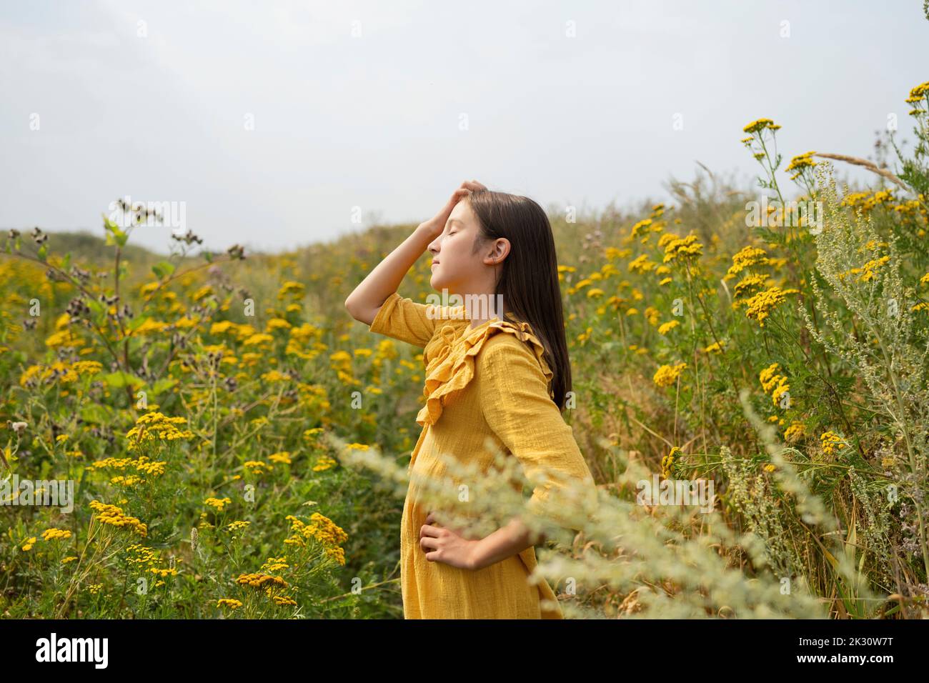 Girl with hand on hip relaxing in field Stock Photo - Alamy