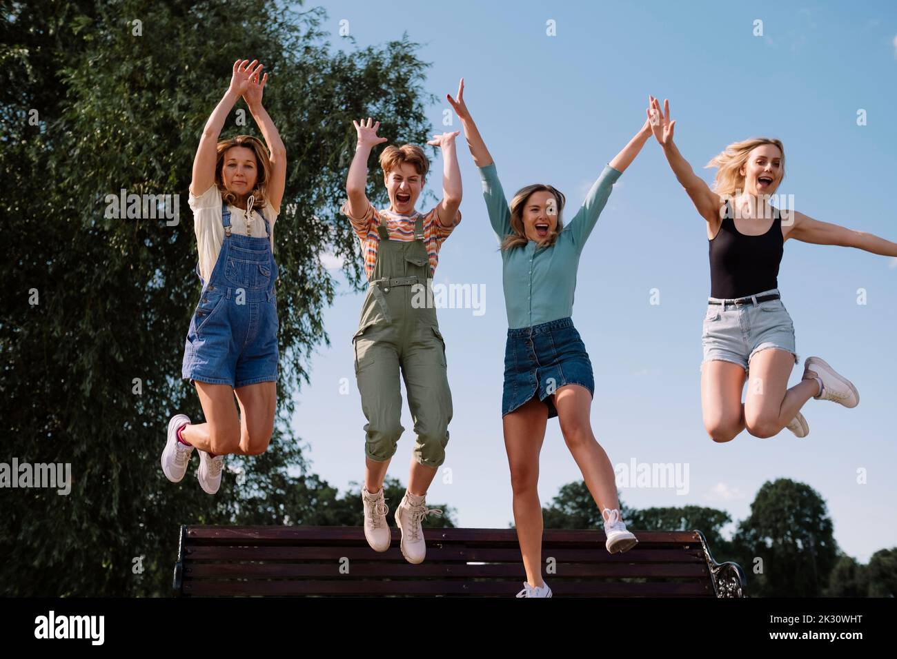 Happy friends jumping together in front of sky at park Stock Photo - Alamy