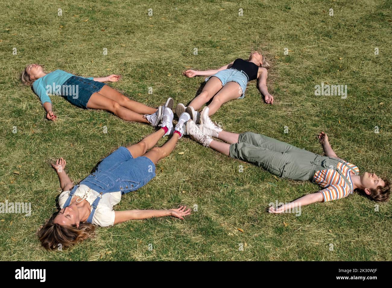 Friends lying together on grass at park Stock Photo