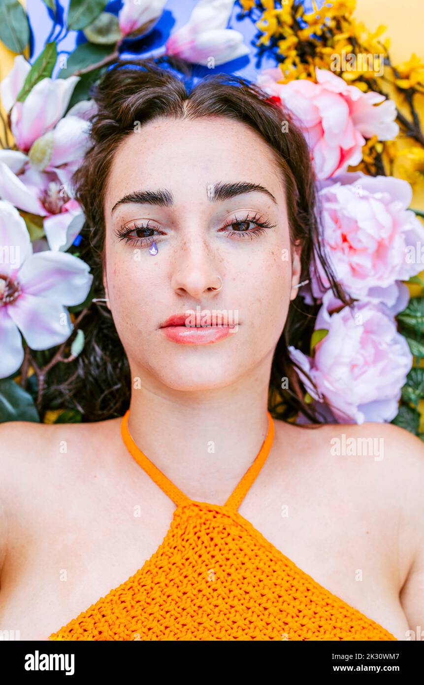Sad woman lying on flowers with teardrop sticker Stock Photo