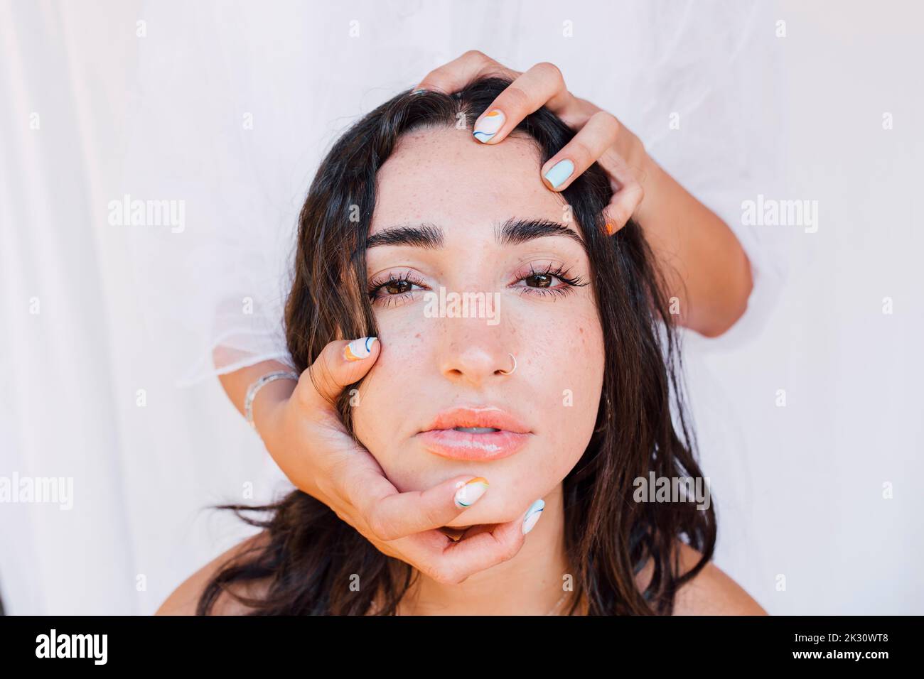 Hands holding head on young woman Stock Photo