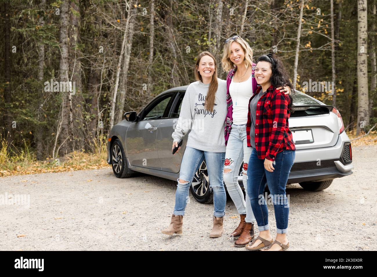 Women walking away from car in forest Stock Photo