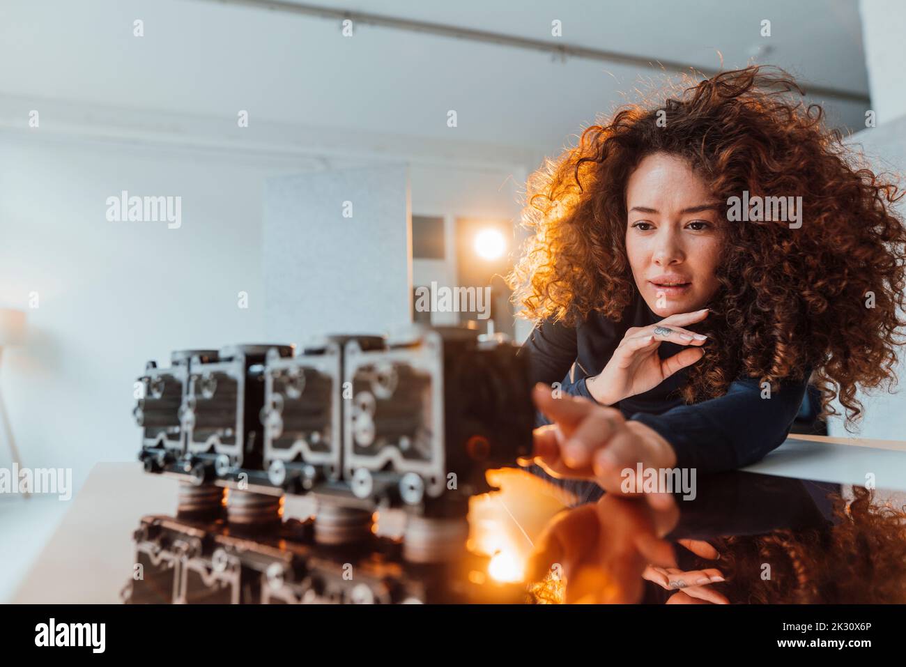 Pink Hair Engineer Young engineer with curly hair analyzing lighting equipment at desk ...