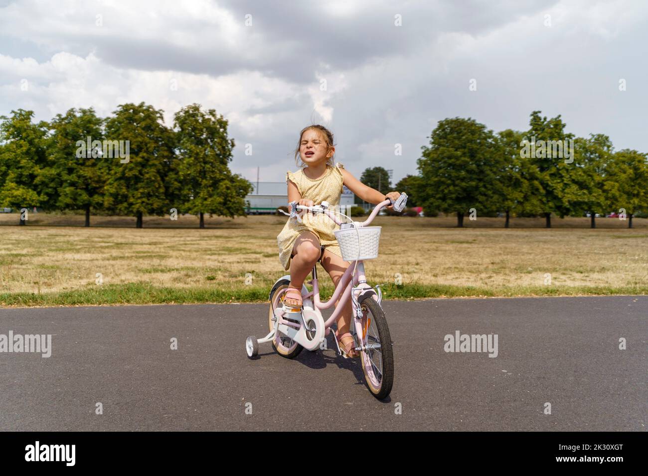 Girl cycling on road at park Stock Photo