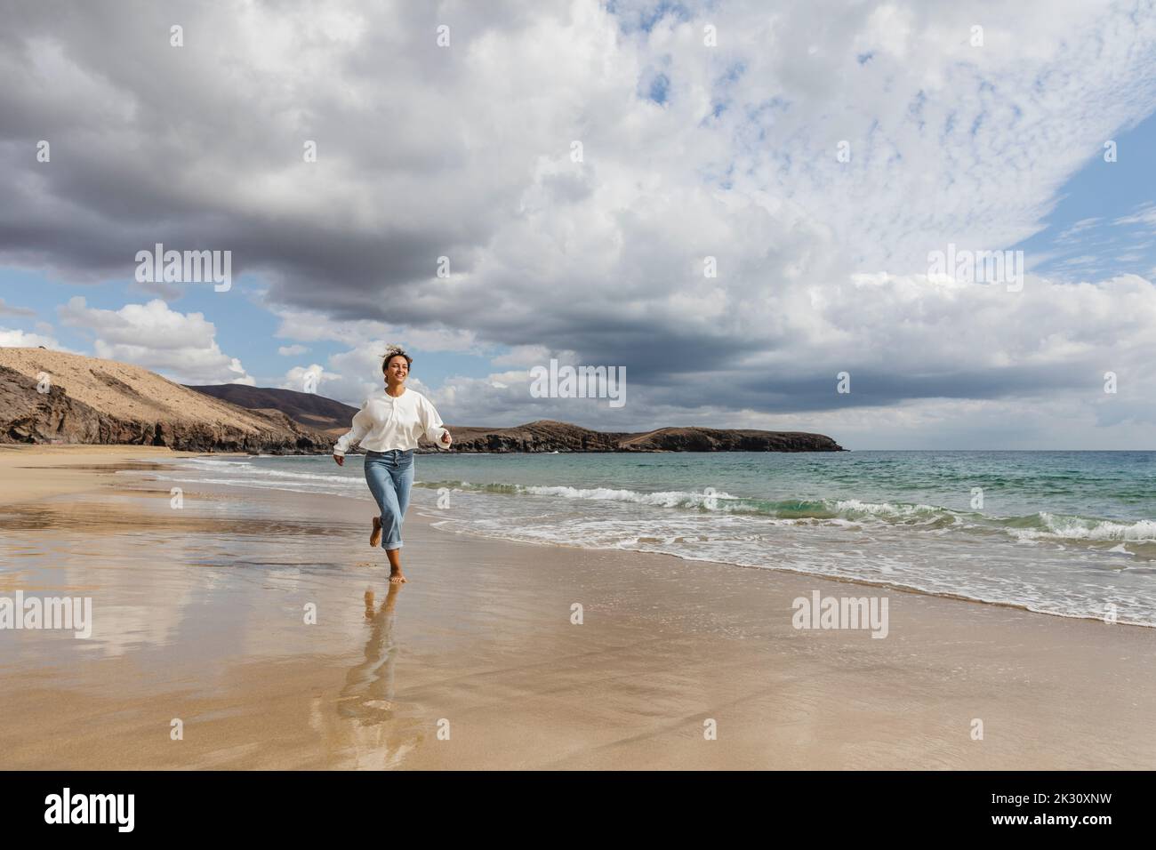 Young woman running on seashore at beach Stock Photo