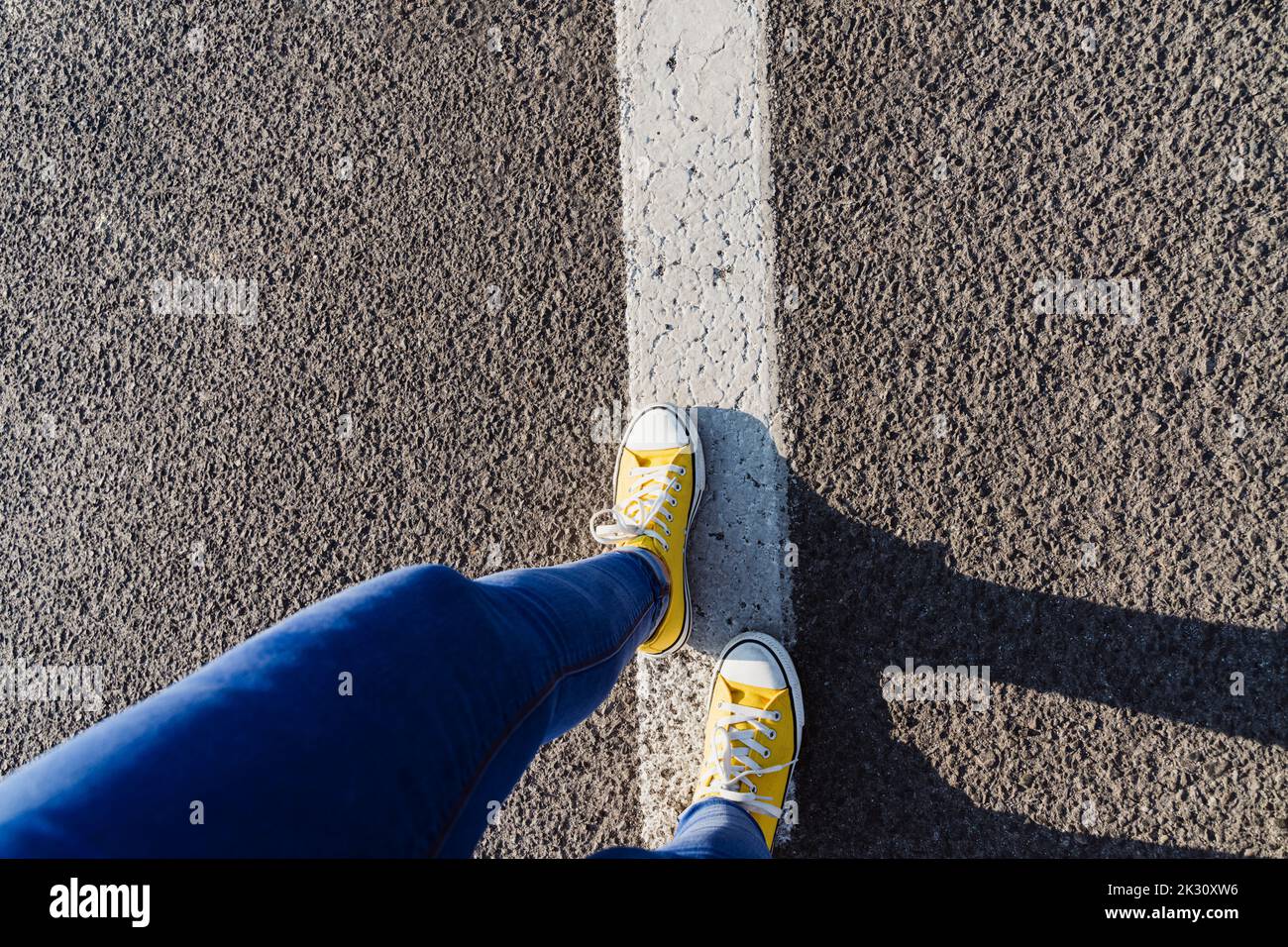 Woman wearing canvas shoes walking on dividing line Stock Photo